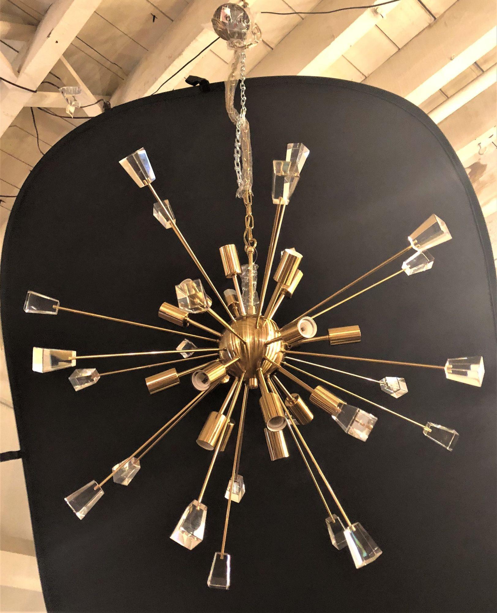 A brass eighteen-light Sputnik chandelier in the Mid-Century Modern style.  Matching canopy and chain that is approximately 54 inches long. Having a brass sphere in the center emanating many brass arrow like rods many with Lucite rectangular caps.
