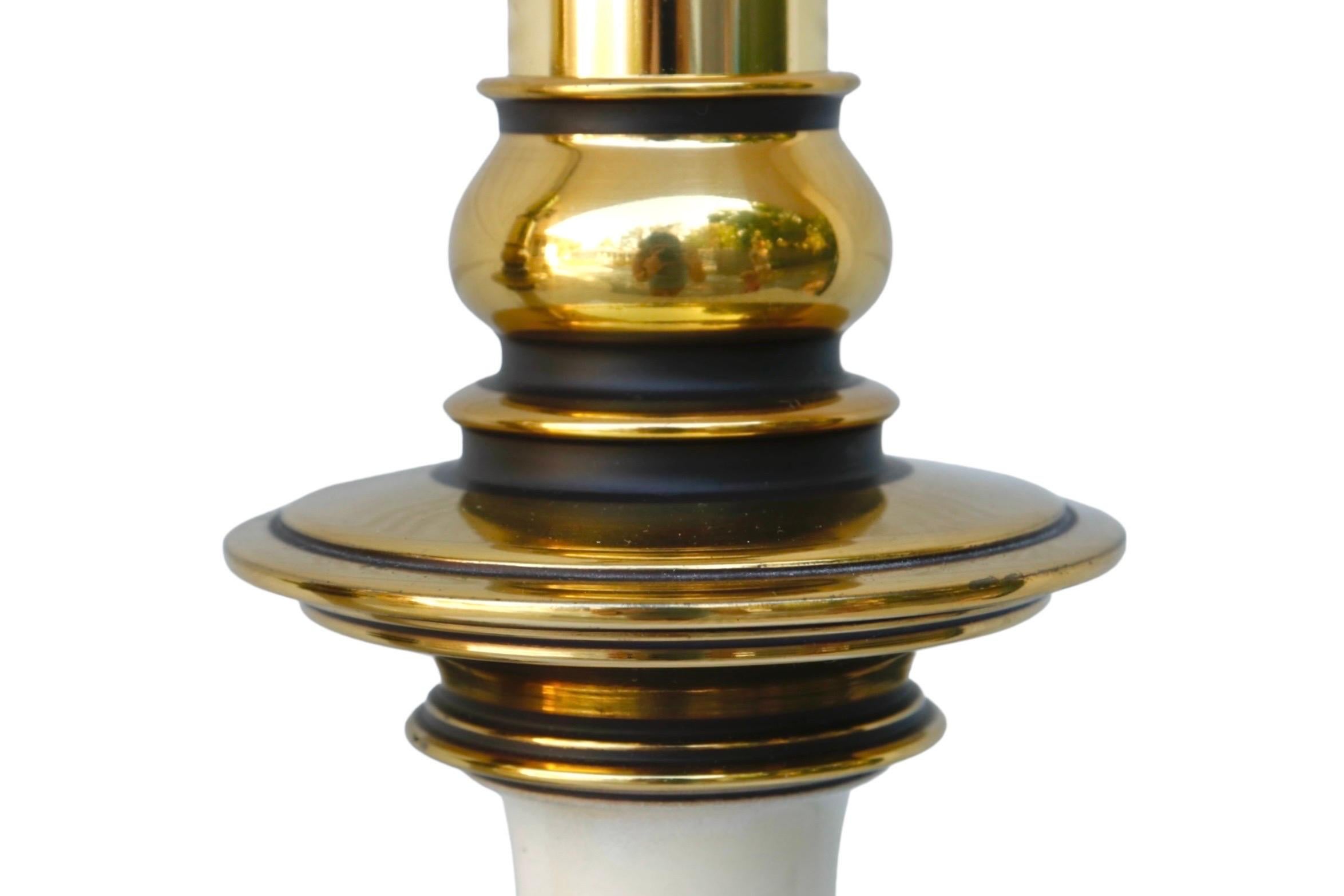 A pair of Regency style baluster shaped table lamps in gold and white by Stiffel. Bright gold colored brass is turned with a central white enameled vase. Each lamp measures 16.5