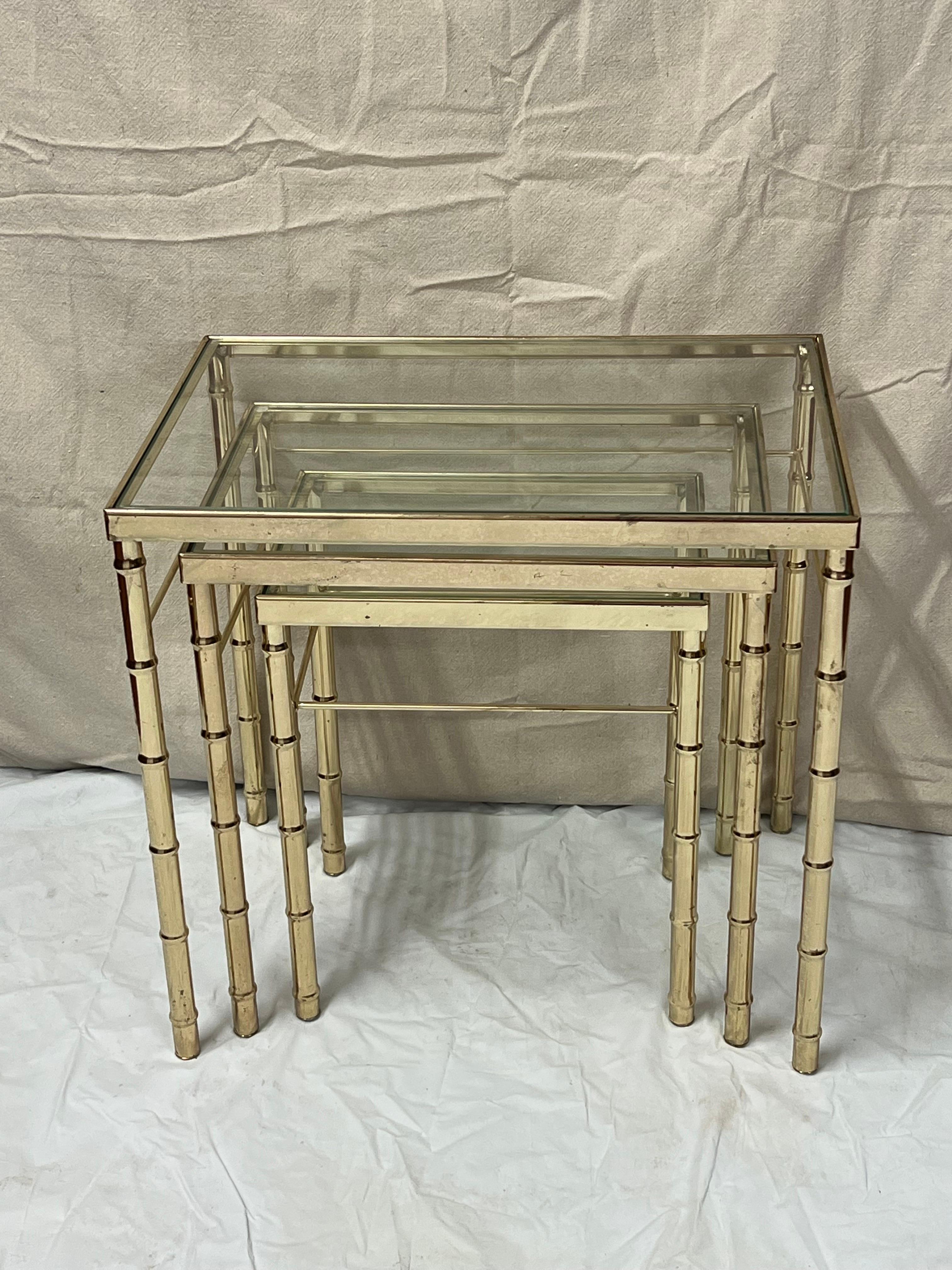Ensemble de tables gigognes en faux bambou et laiton. Utilisez les trois ensemble ou séparez-les selon vos besoins. Les dessus en verre transparent sur les trois. hauteur de 21