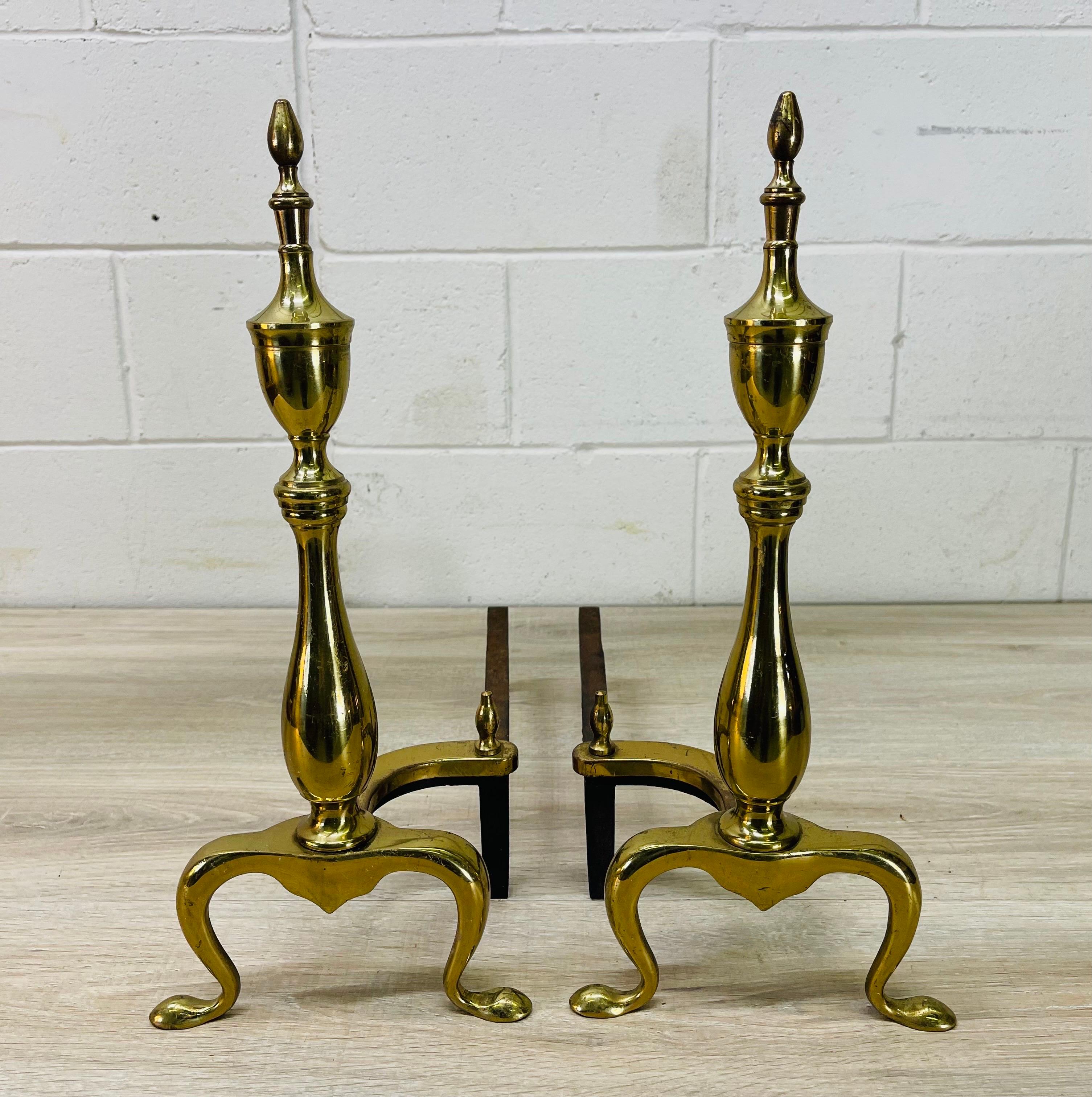 Vintage 1960s pair of Federal style brass fireplace andirons. They are tall and will hold a good amount of wood. The andirons have a sleek and timeless design. No marks.