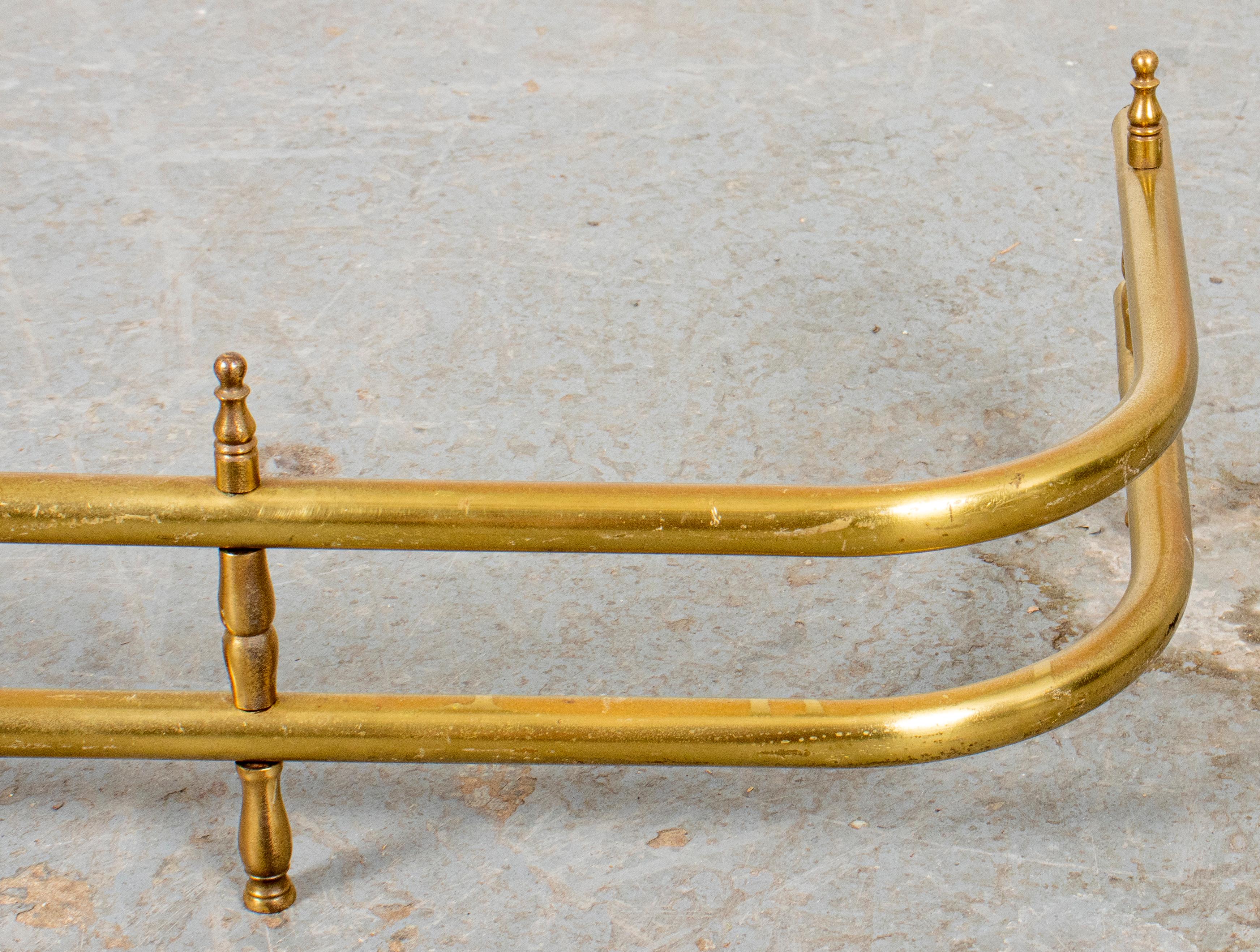 Brass fender of curved outline and with double smooth rail. Measures: 6.5” H x 47” W x 15” D.