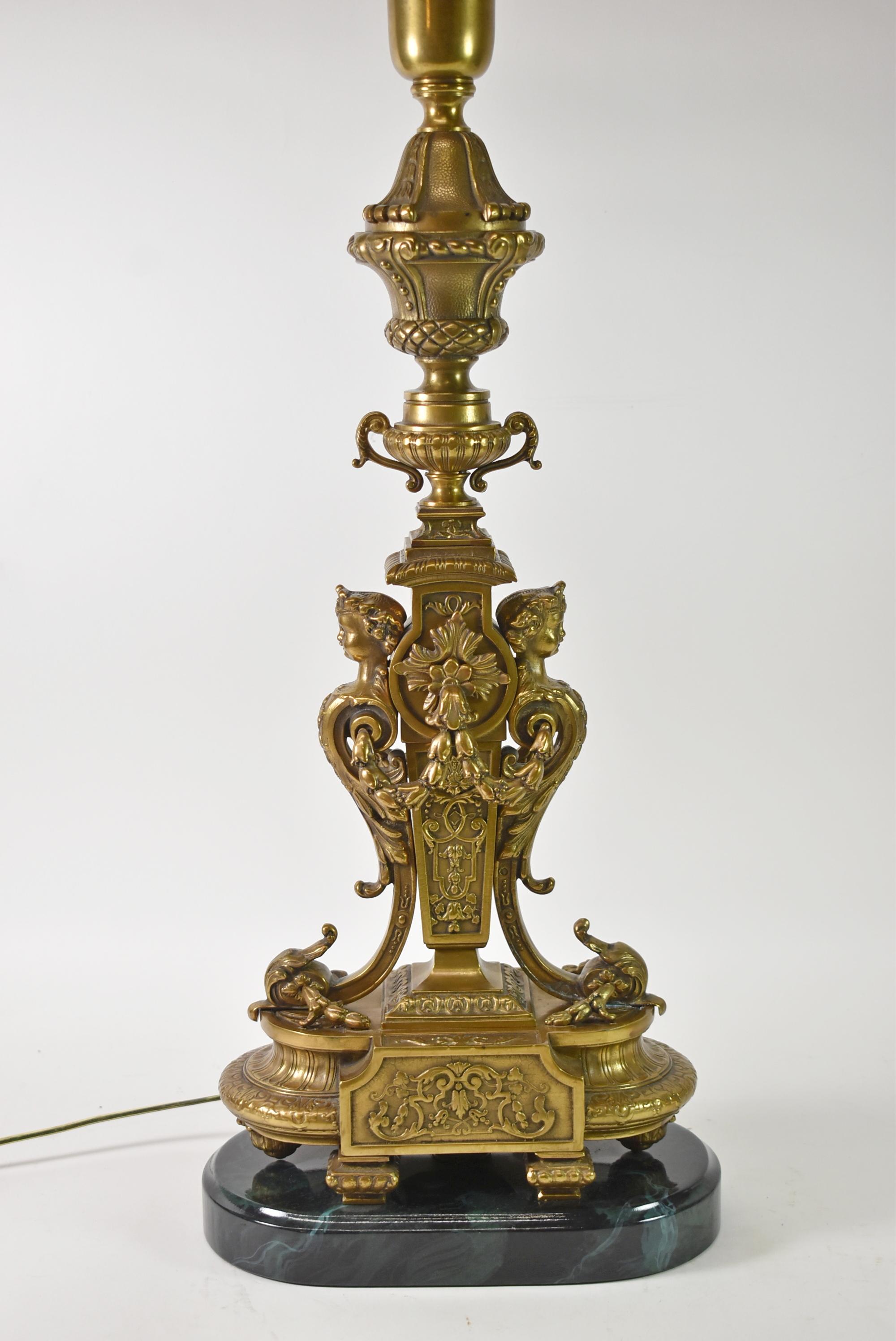 This beautiful Italian Renaissance Table lamp is an urn form with double handles. The body of the lamp is decorated with female figure heads with crowns and leaf form swags. The wiring has been redone with inline switch and socket pulls. The base is