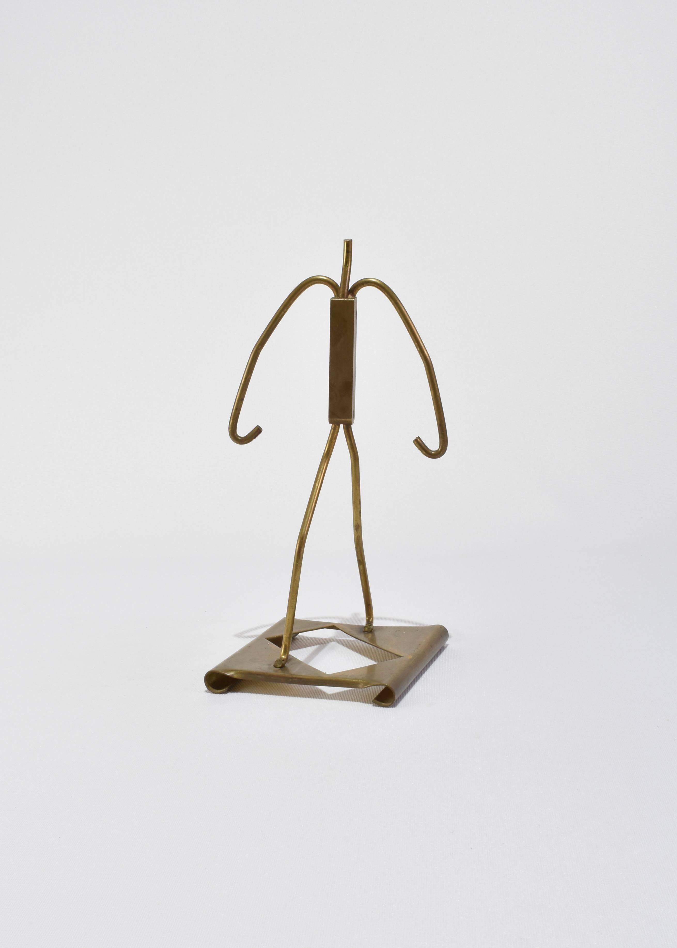 Sculpture minimaliste en laiton représentant un personnage debout stylisé. Formé d'une tige de laiton pliée et soudée avec une base géométrique découpée.