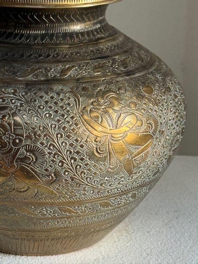 The Antique Brass Water Drinking Pot, or Lota, showcases intricate engraving on durable brass, originating from South Asia. Its rounded body with a narrow neck facilitated daily water usage, while its designs reflected cultural identity and