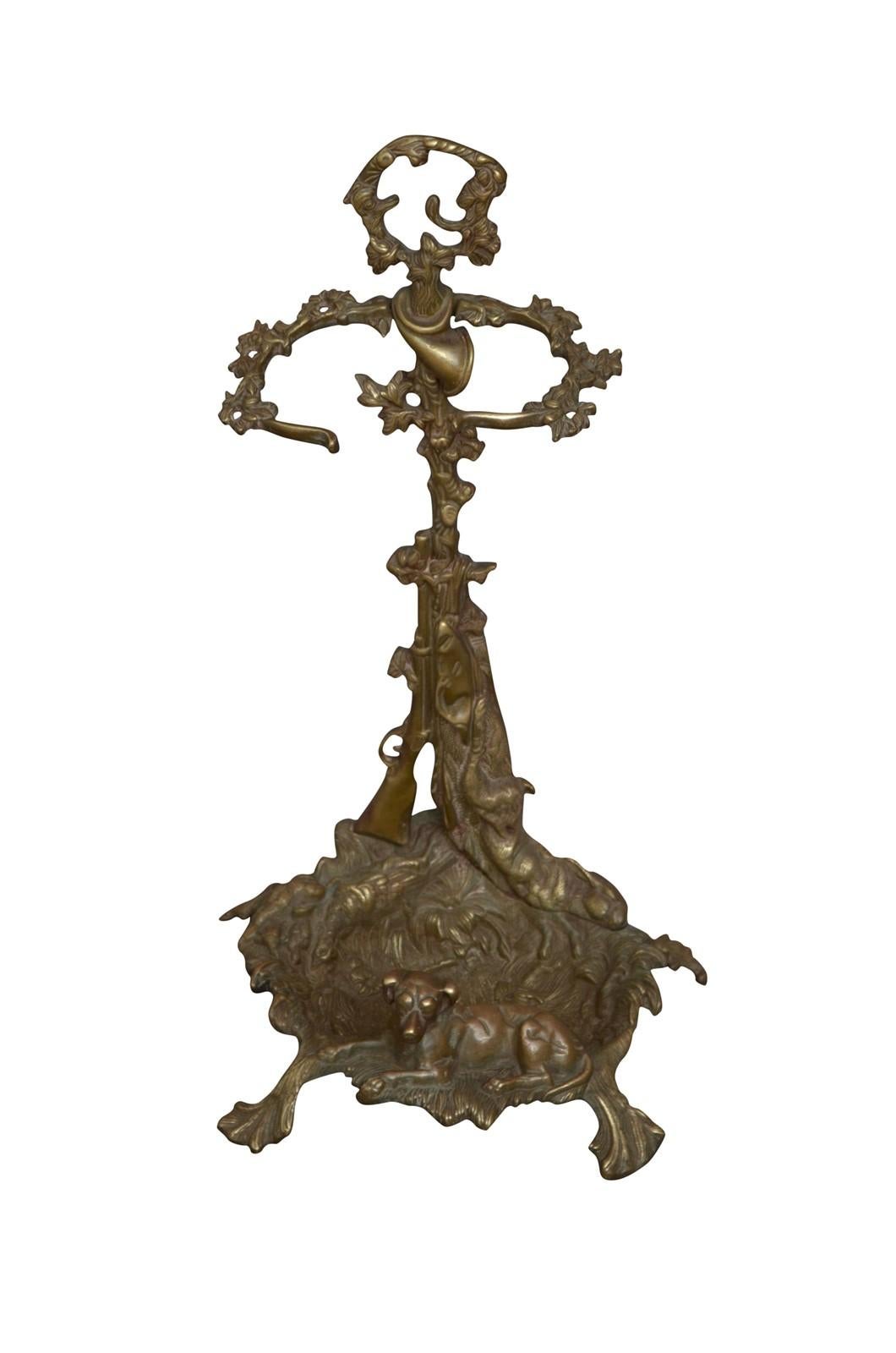 K0551 Soporte de latón vintage para hierros de fuego con pinzas, pala y atizador, el soporte representa una escena de caza con un perro, una liebre y follaje, todo en estado casero con pequeñas reparaciones históricas. El Este soporte antiguo sería
