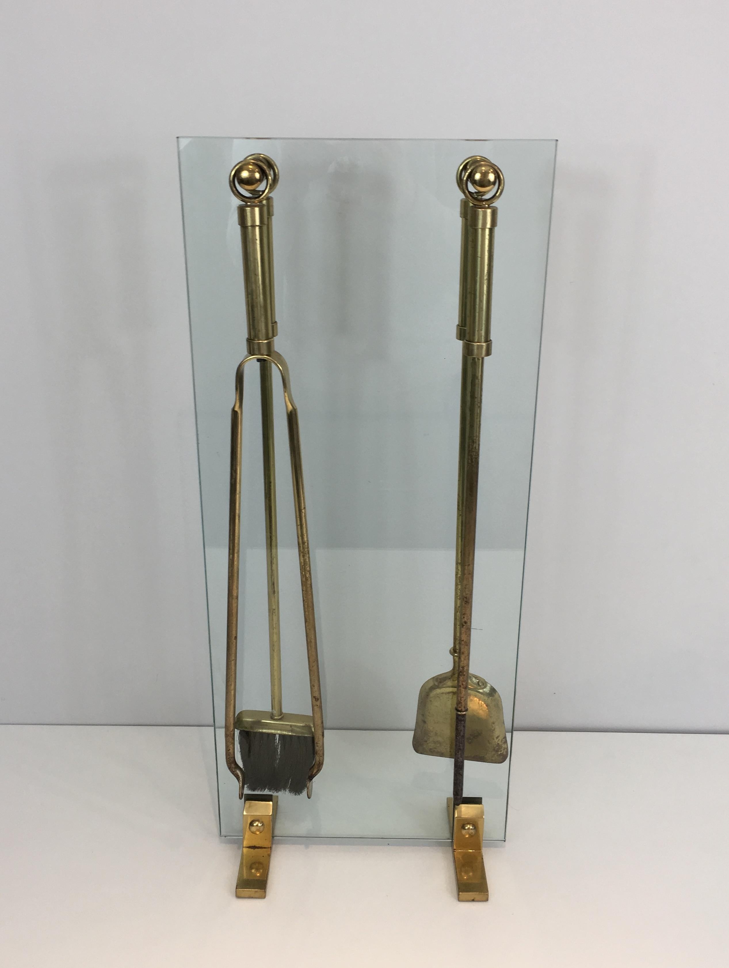 This nice set of fire place tools stand on a glass and brass stand, which is very elegant (Glass has a little chip on a bottom corner, which can be sanded). French work, circa 1970.