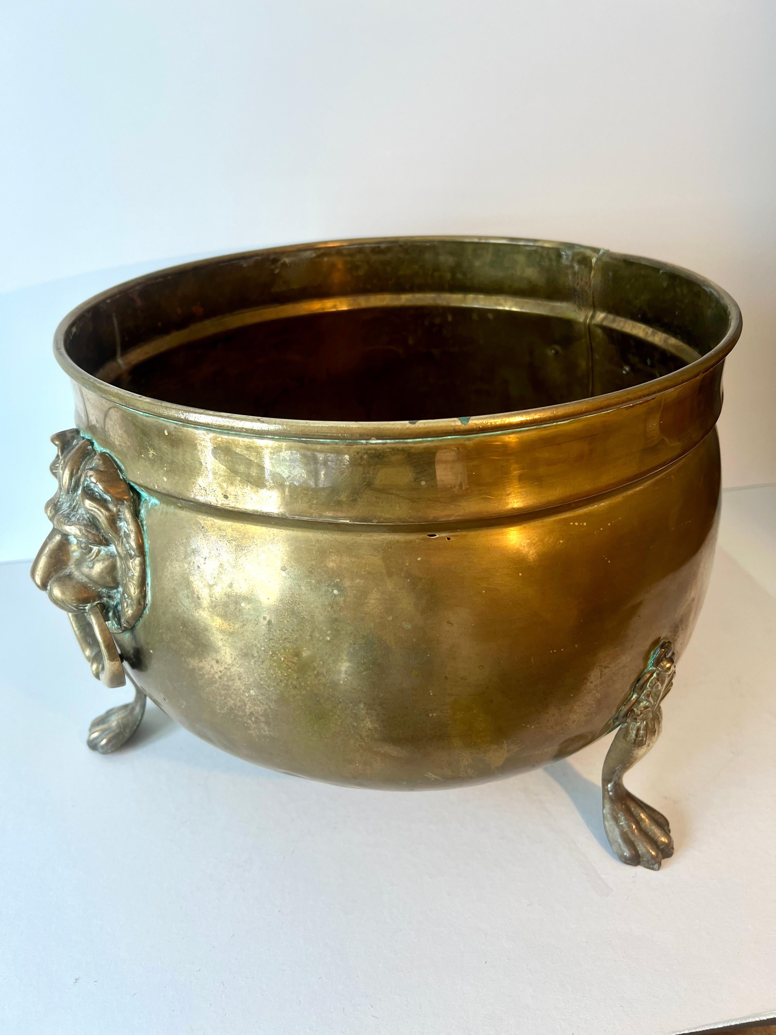 An English Brass Pot / Planter or Chimney Coal Wood Bin.  The bin has handles with well designed Lions with rings.

An attractive addition to the fireplace to hold wood, kindling or paper.  Originally from the UK, the bin has a beautiful patination