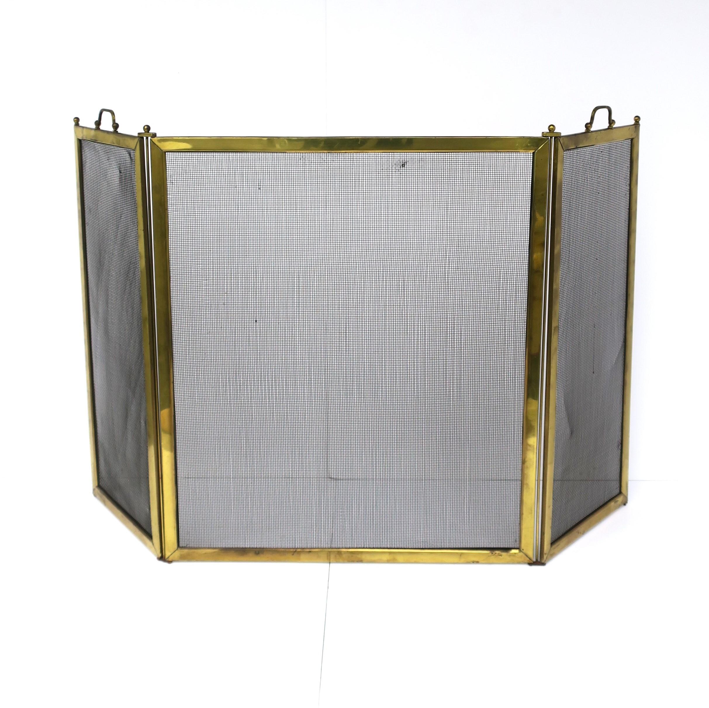 A brass frame fireplace screen with handles and ball finial detail, circa mid-20th century. Screen is a trifold with brass frame, black mesh metal screen, brass handles and finials. The trifold is nice because it allows no obstruction to front of