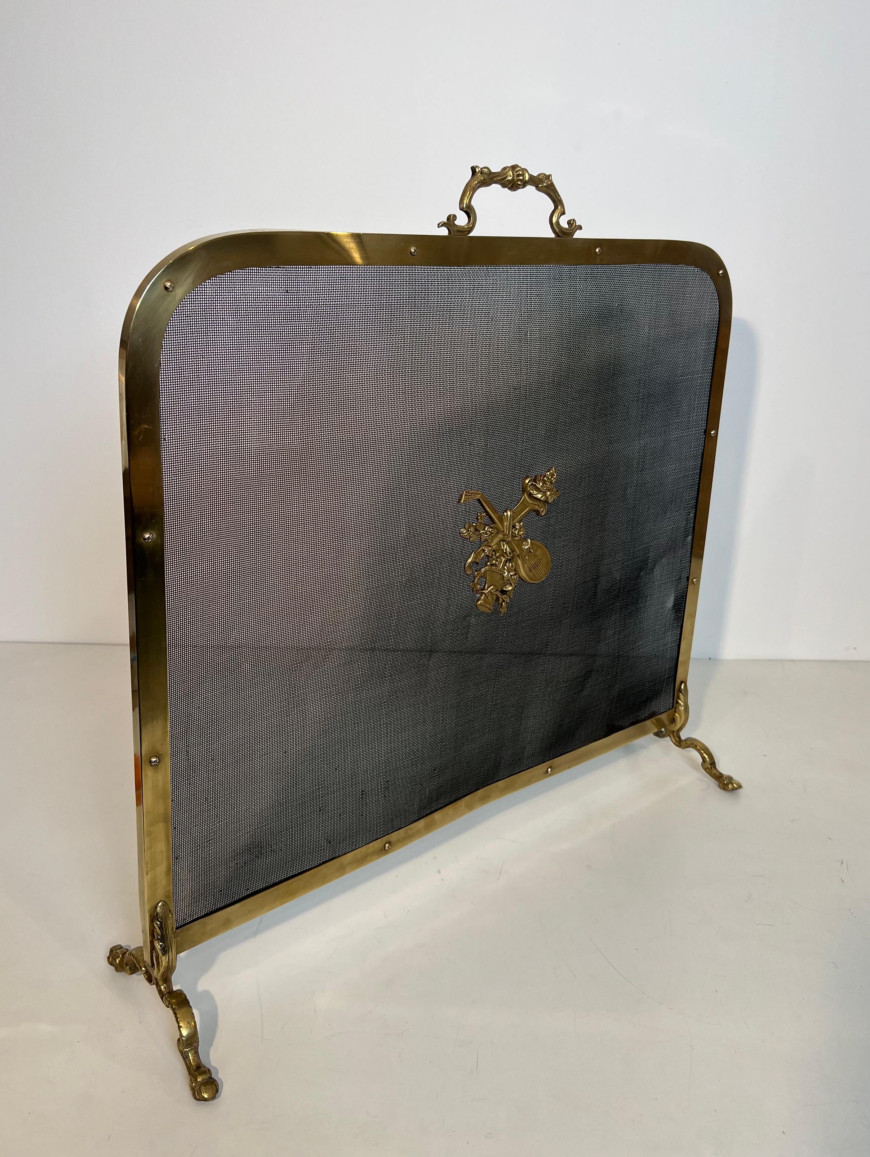 Questo paravento per caminetto in stile neoclassico è realizzato in ottone e rete. È decorato con un mandolino, con un  bouquet di fiori e basi di zoccoli di cavallo. Si tratta di un'opera francese marcata 