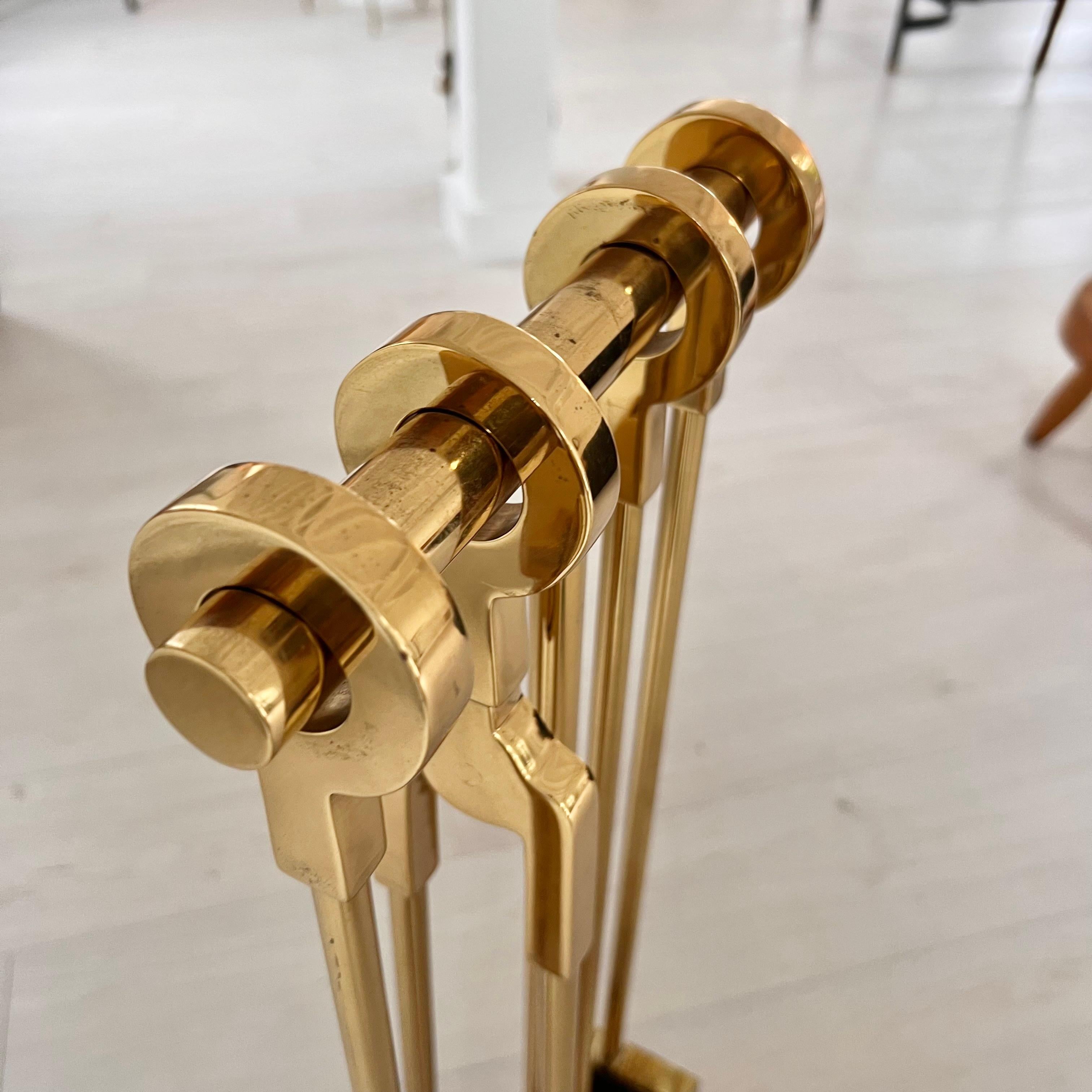A stunning set of brass post-modern fireplace tools by Danny Alessandro. Bold and elegantly refined cast fire tools with ring handles in brass, comprising four implements each with a circular 