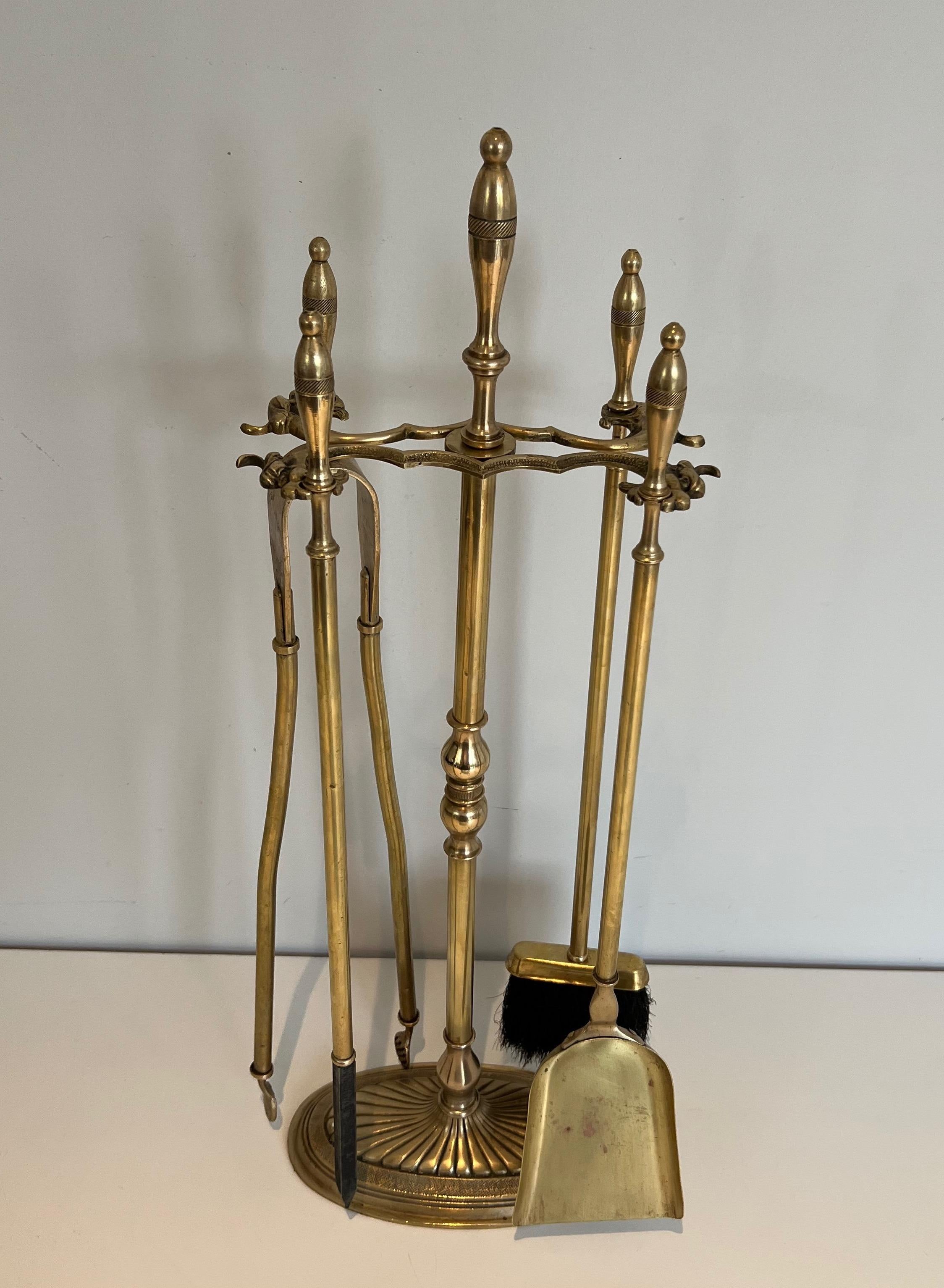 This neoclassical style fireplace tools on stand are made of brass. This is a French work. Circa 1970.
