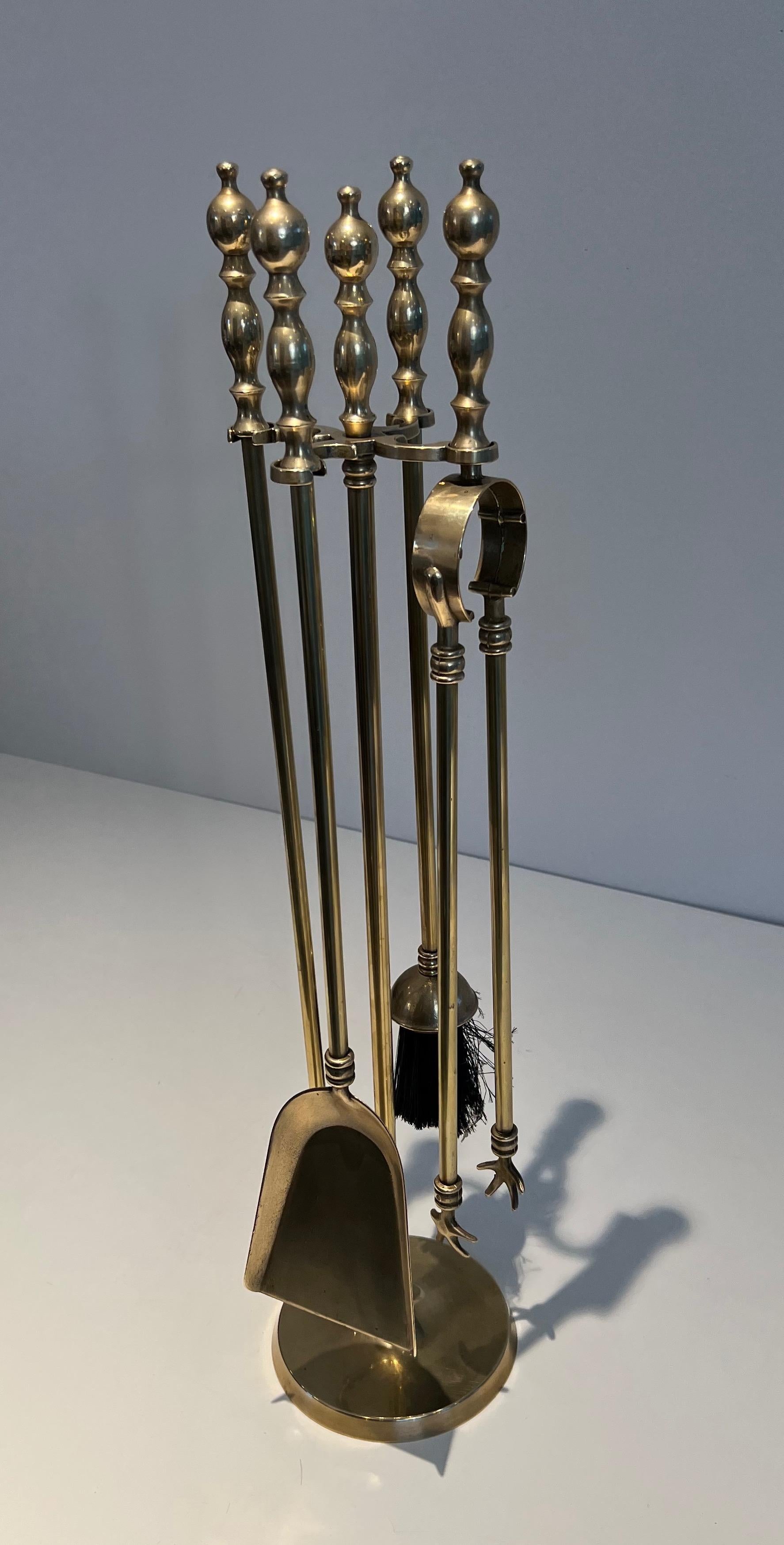 This neoclassical style fireplace tools on stand is made of brass. This is a French work. Circa 1970.