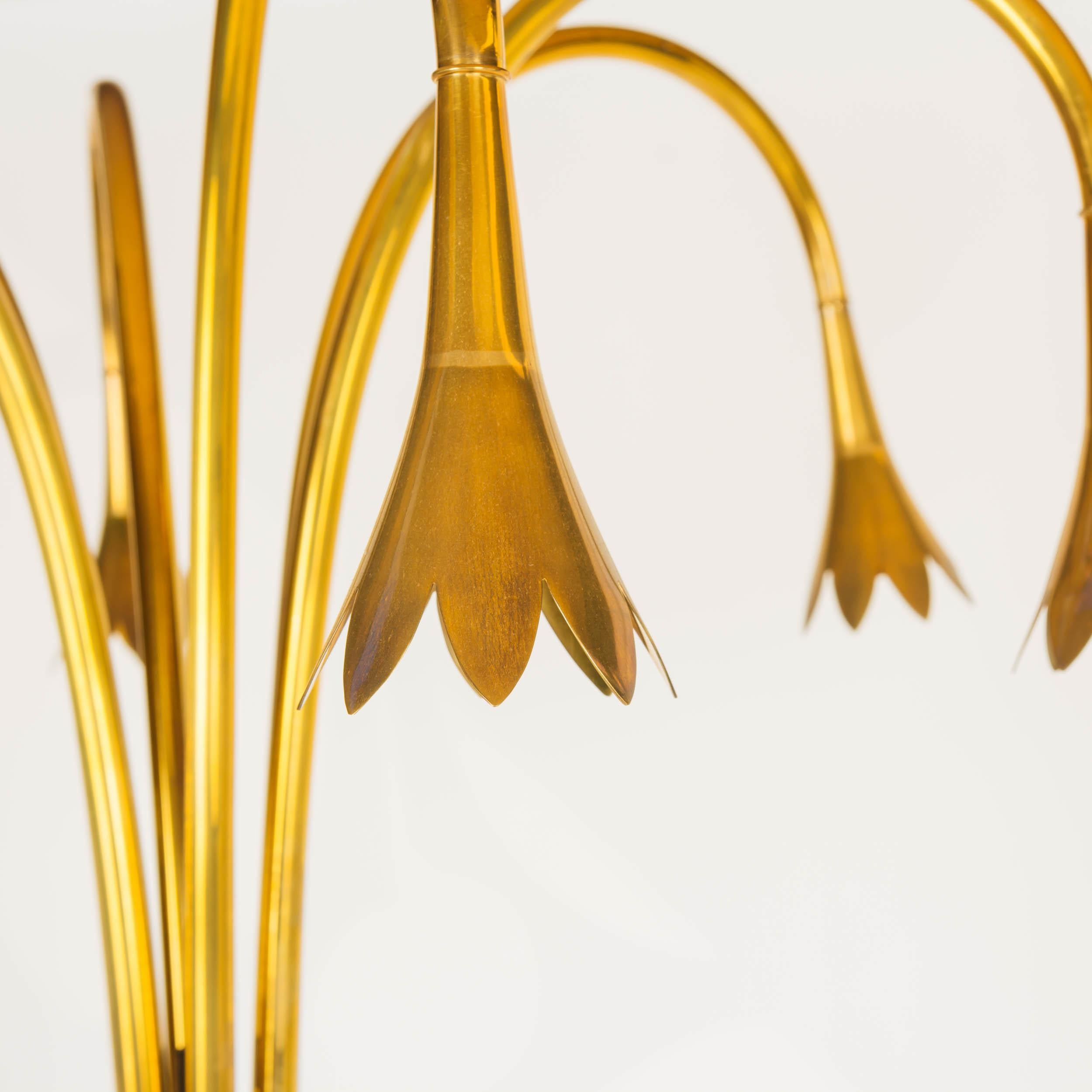 A brass floor lamp with arms in the form of an arrangement of wilting tulip stems atop a verdís gres marble base.