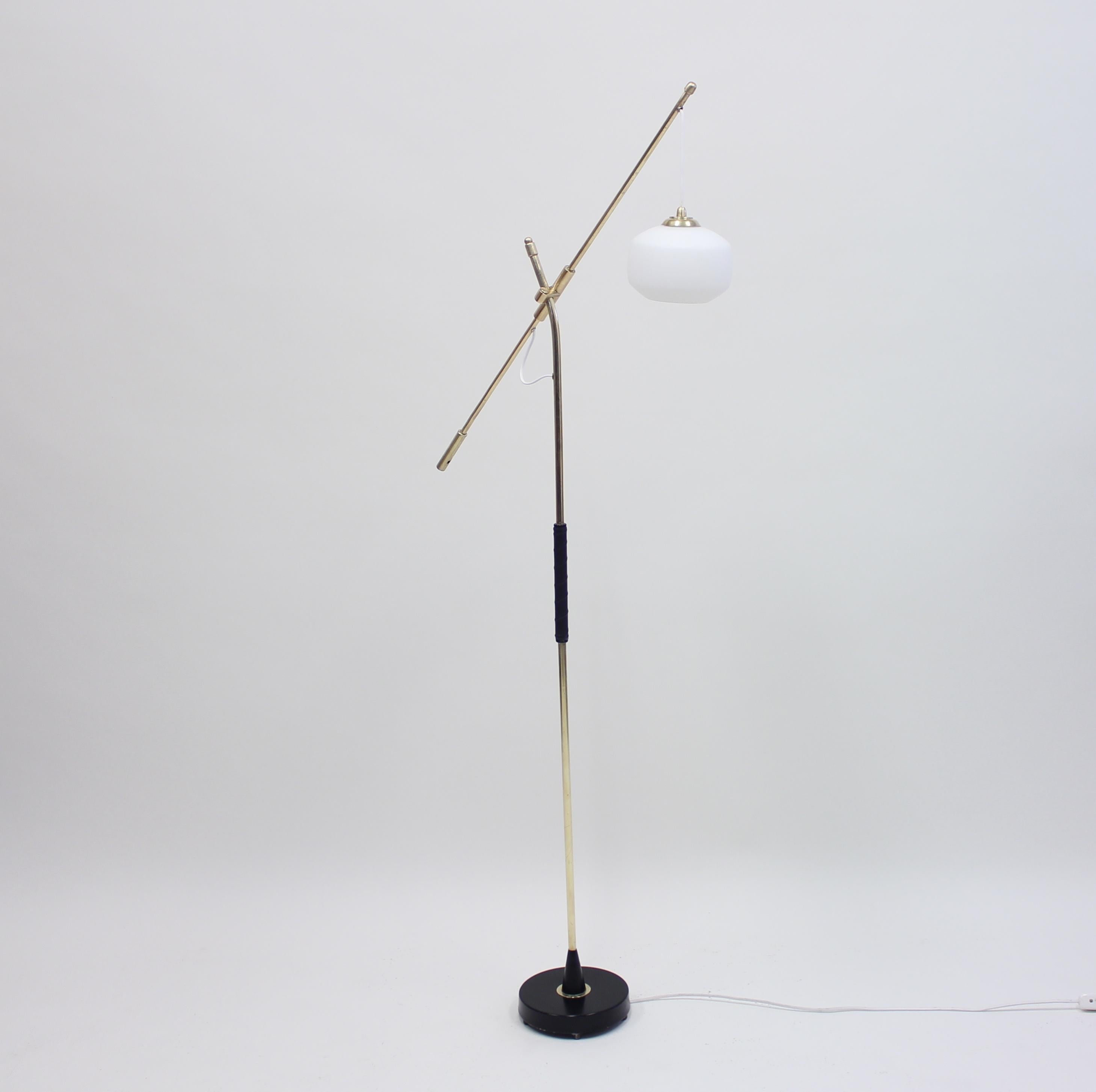 Height adjustable midcentury Swedish floor lamp from Falkenbergs Belysning with a counter weight function and an opaline round glas shade. Adjustable between 145-153 cm. Construction and stem in brass on a metal base. Very good vintage condition.