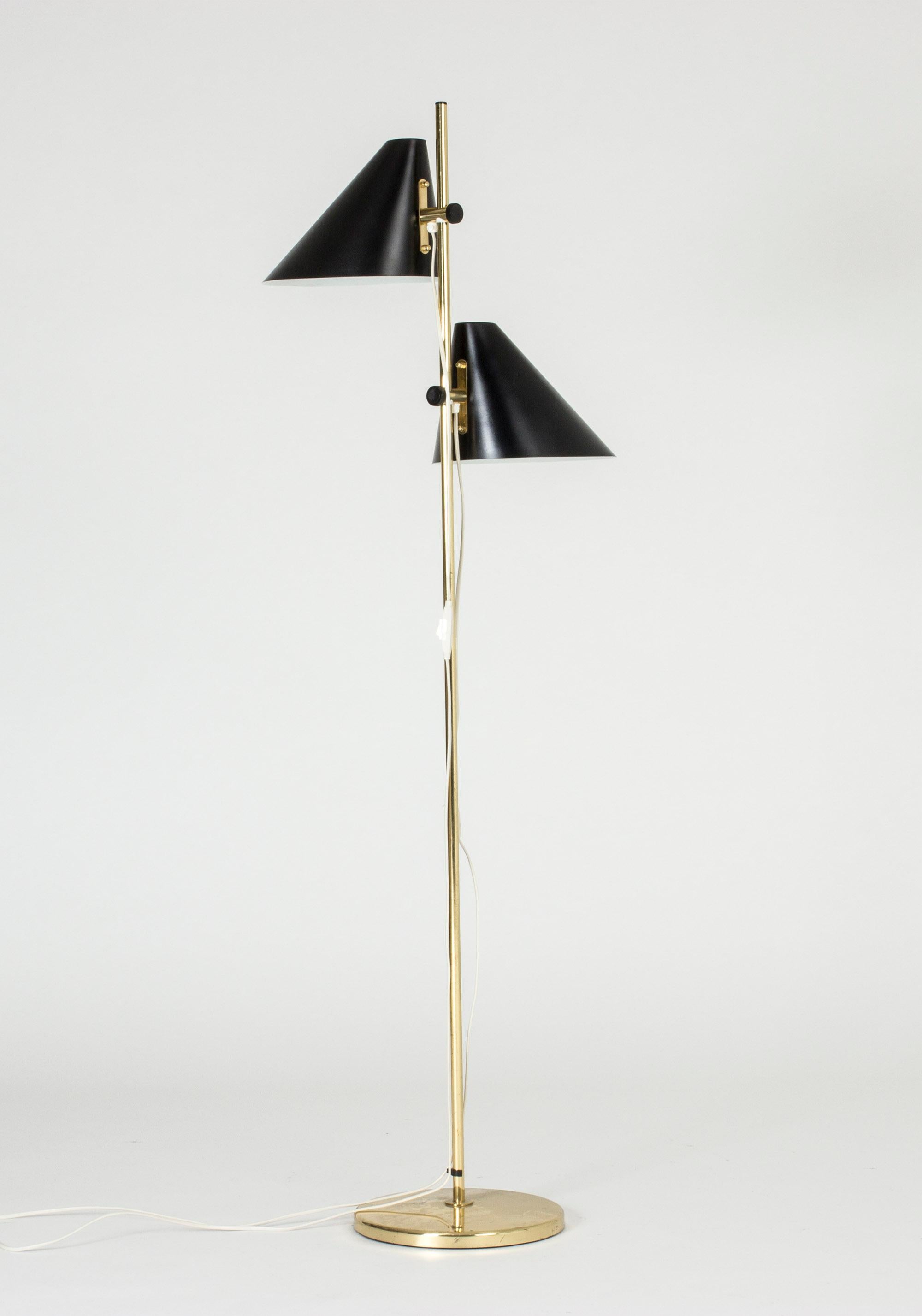 Striking brass floor lamp with two lamp shades by Hans-Agne Jakobsson. The black lacquered shades can be adjusted to different vertical positions and can also be turned around the pole.