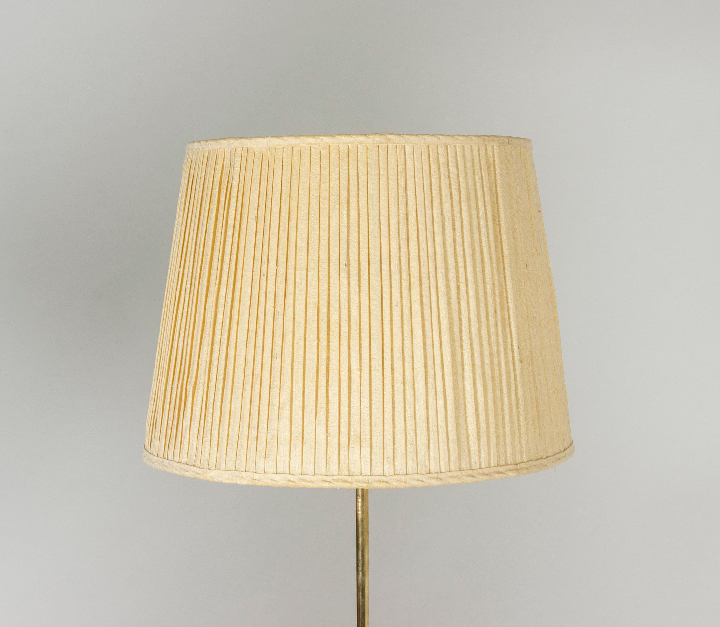 Elegant brass floor lamp by Josef Frank with adjustable height. Original plissé silk lamp shade.