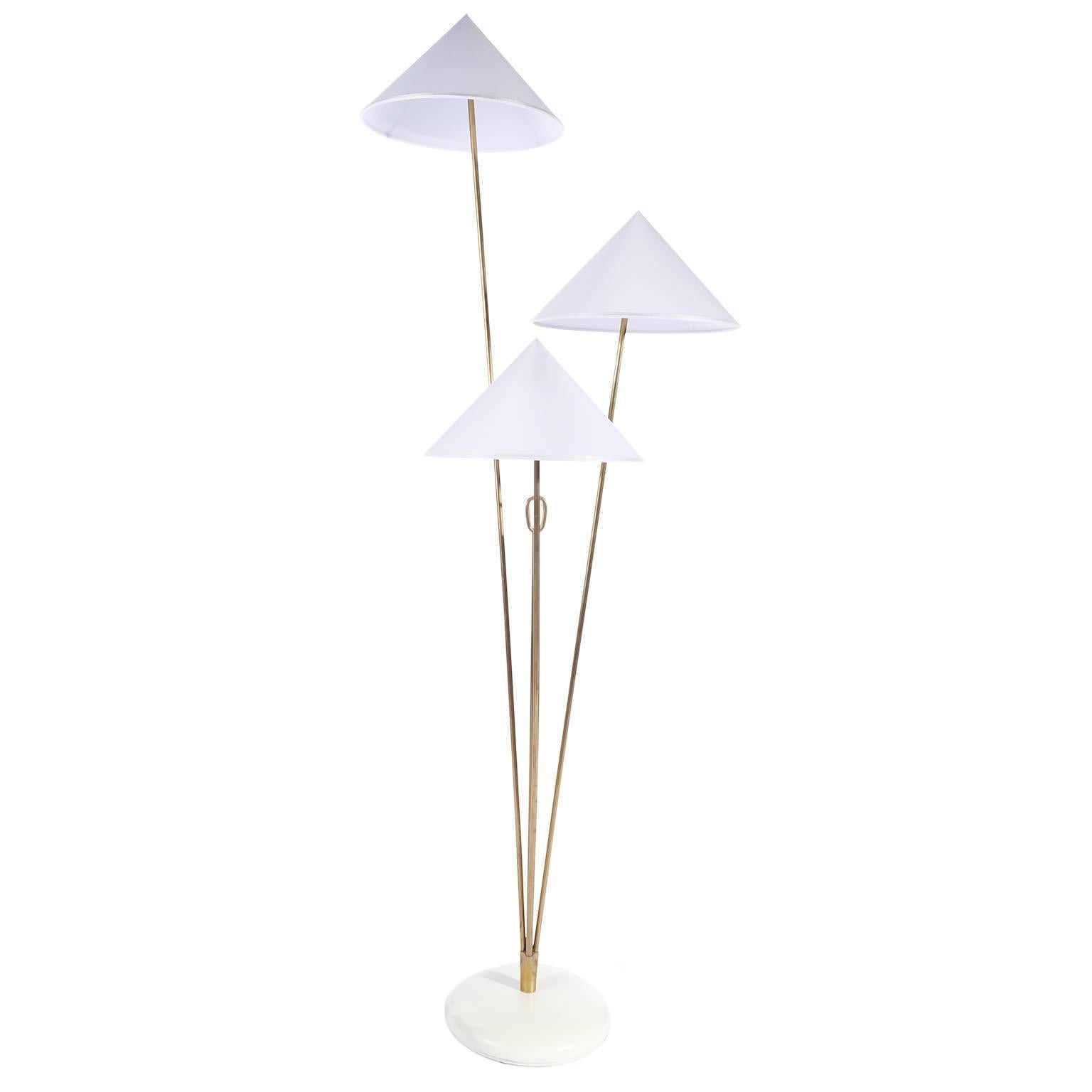A brass floor lamp with cone shaped lampshades by Rupert Nikoll, Vienna, Austria, manufactured in midcentury, circa 1960 (late 1950s or early 1960s). 
The stand is made of three brass rods in different lengths, a shorter brass rod with a handle,