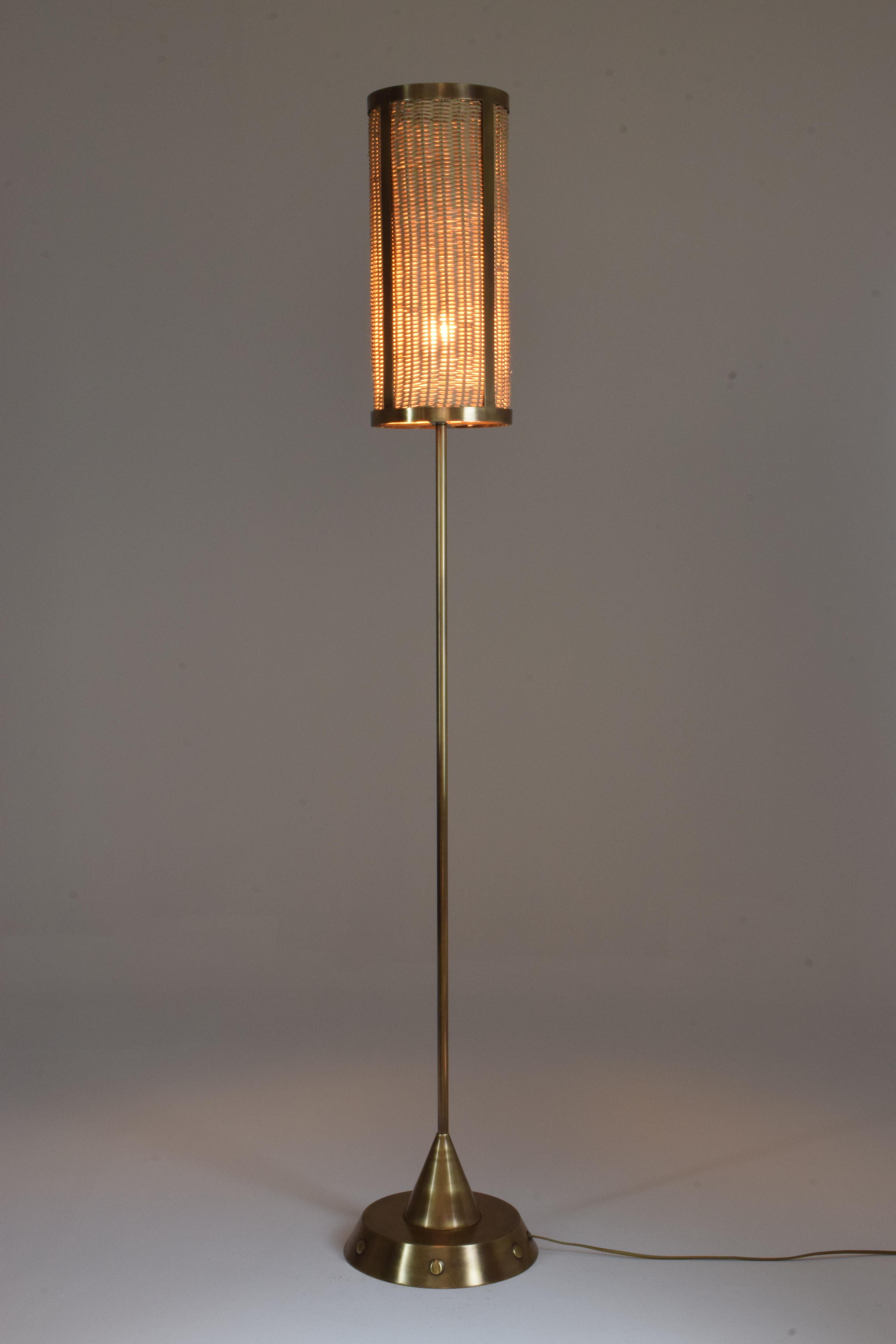 Solid brass floor lamp handcrafted with engraved details, standing on handwoven cylinder wicker shade.
CF-M.

