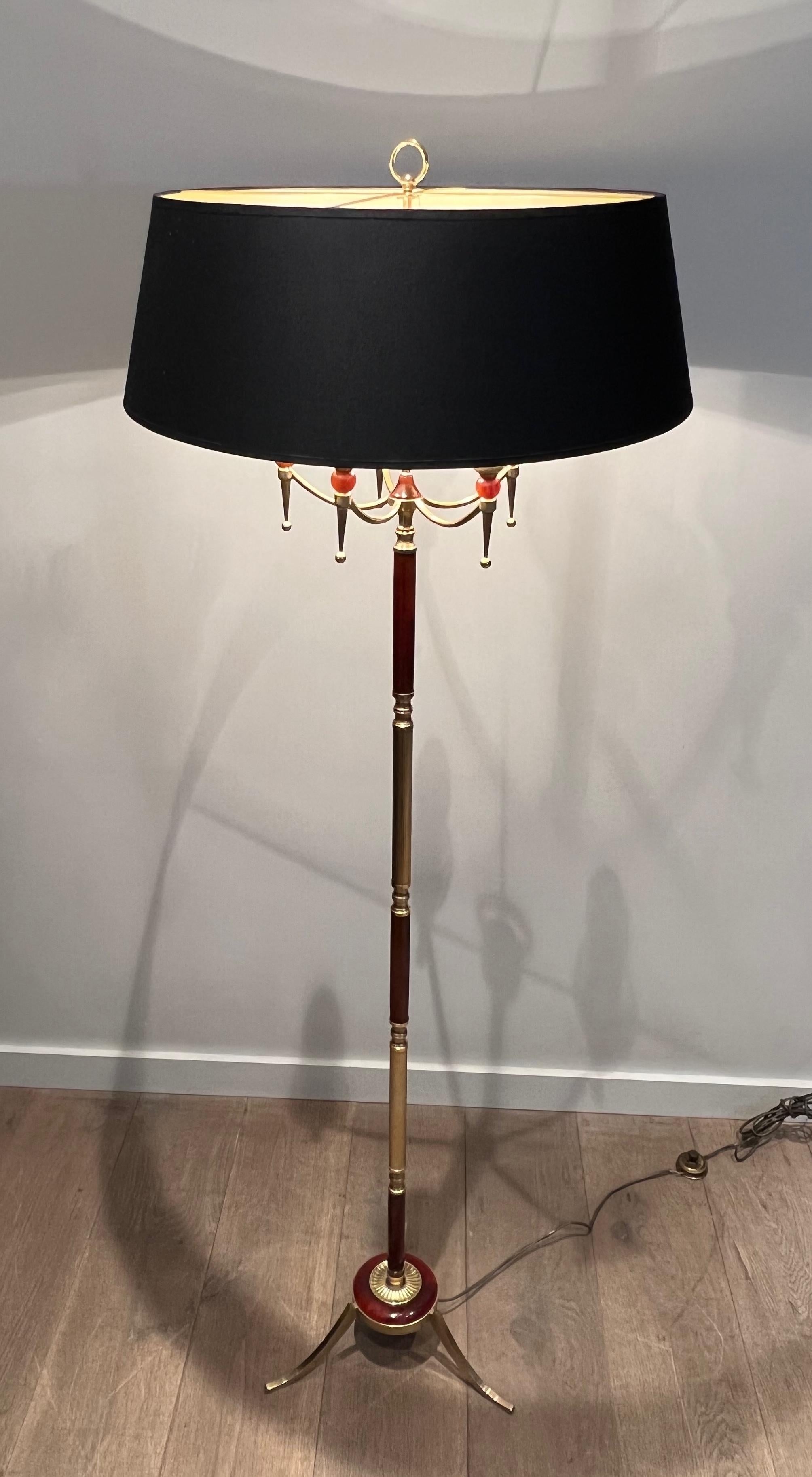 Esta lámpara de pie de estilo neoclásico es de latón con elementos de lucita roja. La lámpara tiene 5 brazos. Se trata de una obra francesa del estilo de la Maison Jansen. Alrededor de 1940