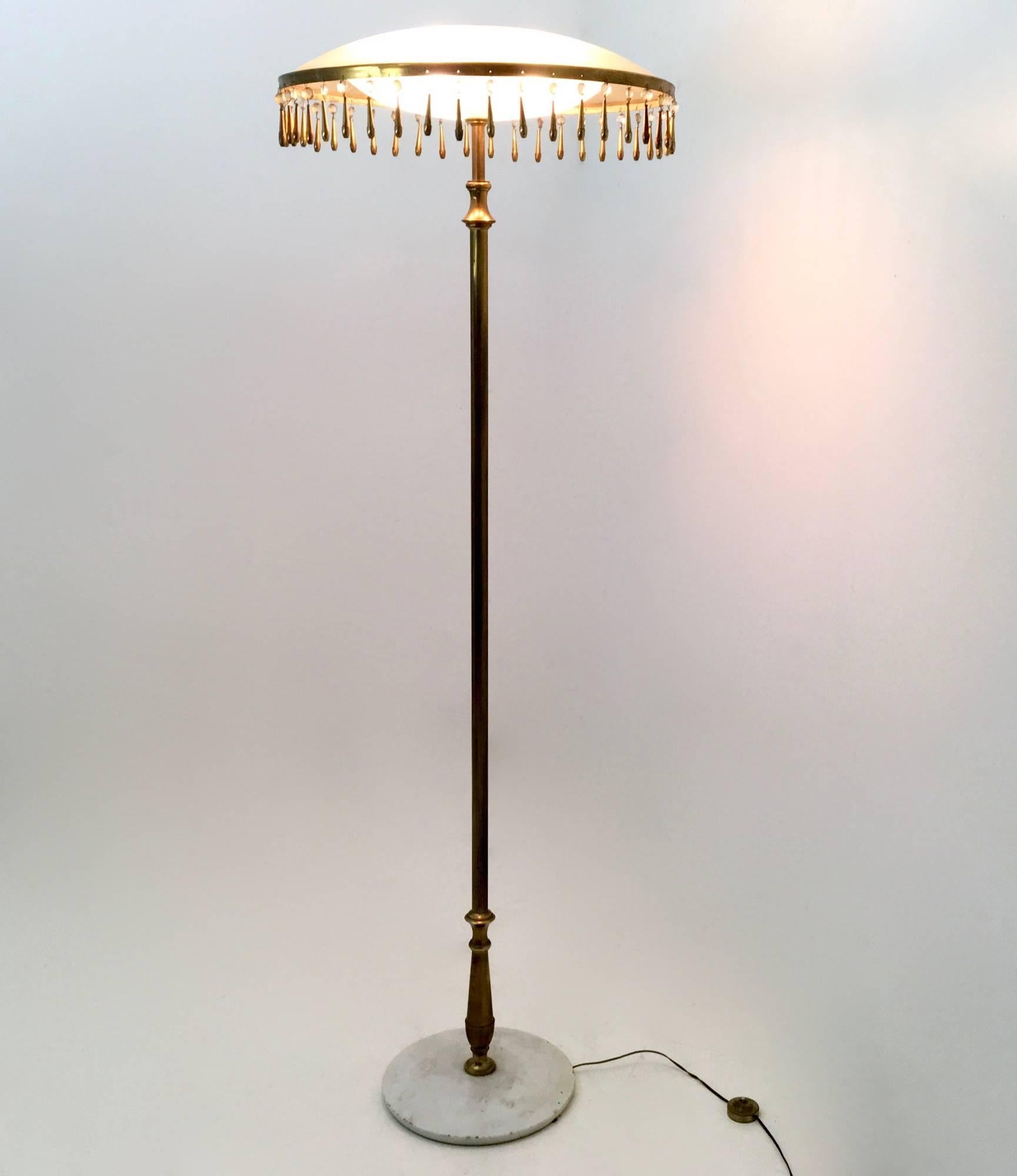1955
This floor lamp features a marble base, a polished brass structure and duplex white opal and frosted glass diffusers.
Its rings is decorated with glass and brass pendants.
It may show slight traces of use, but there aren't any missing parts or