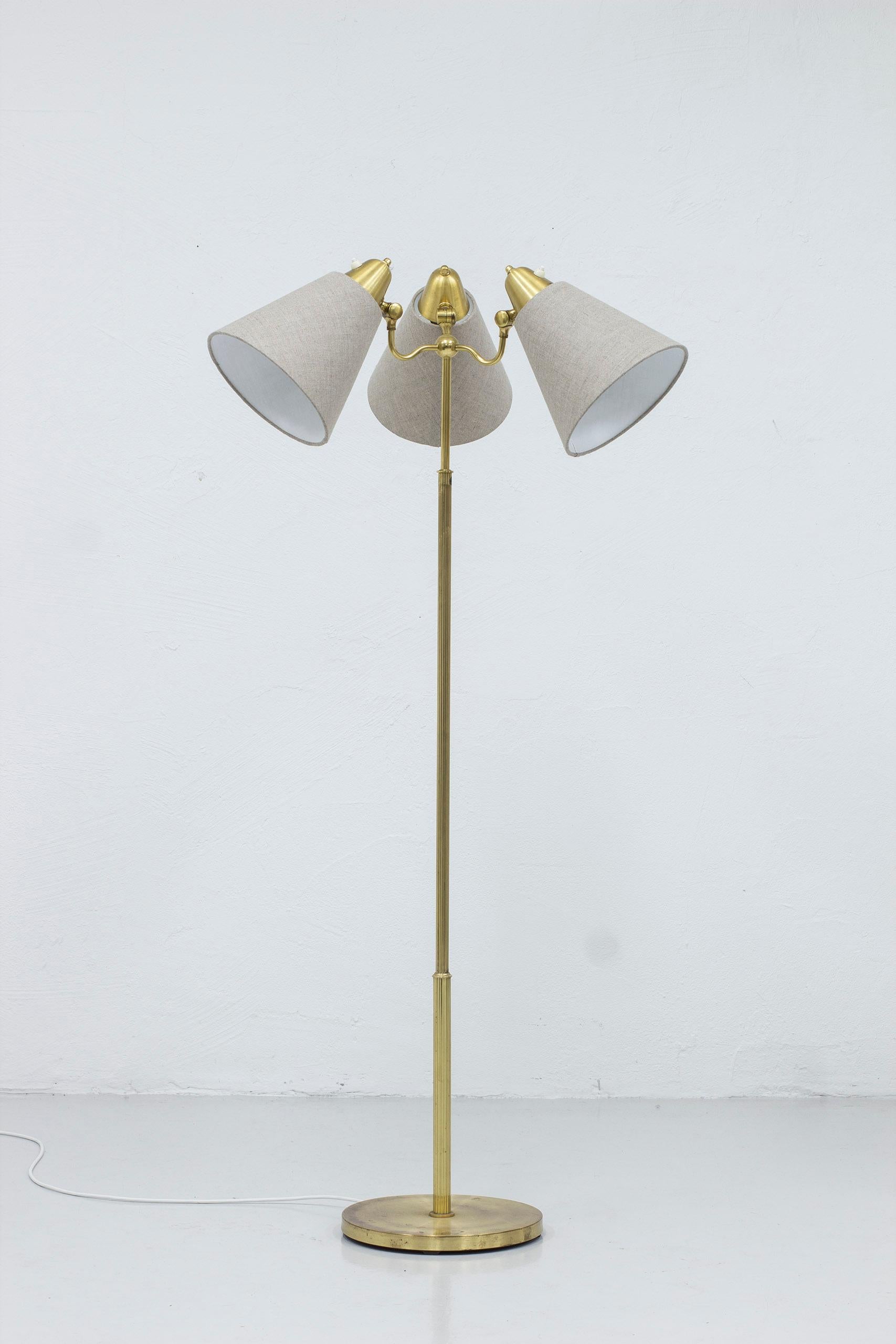 Floor lamp model 324 produced by Armaturhantverk. Made in Göteborg, Sweden during the 1940s. Made from brass with three adjustable shades. New lamp shades in grey linen fabric Light switches on all three lamps in working order. Good vintage