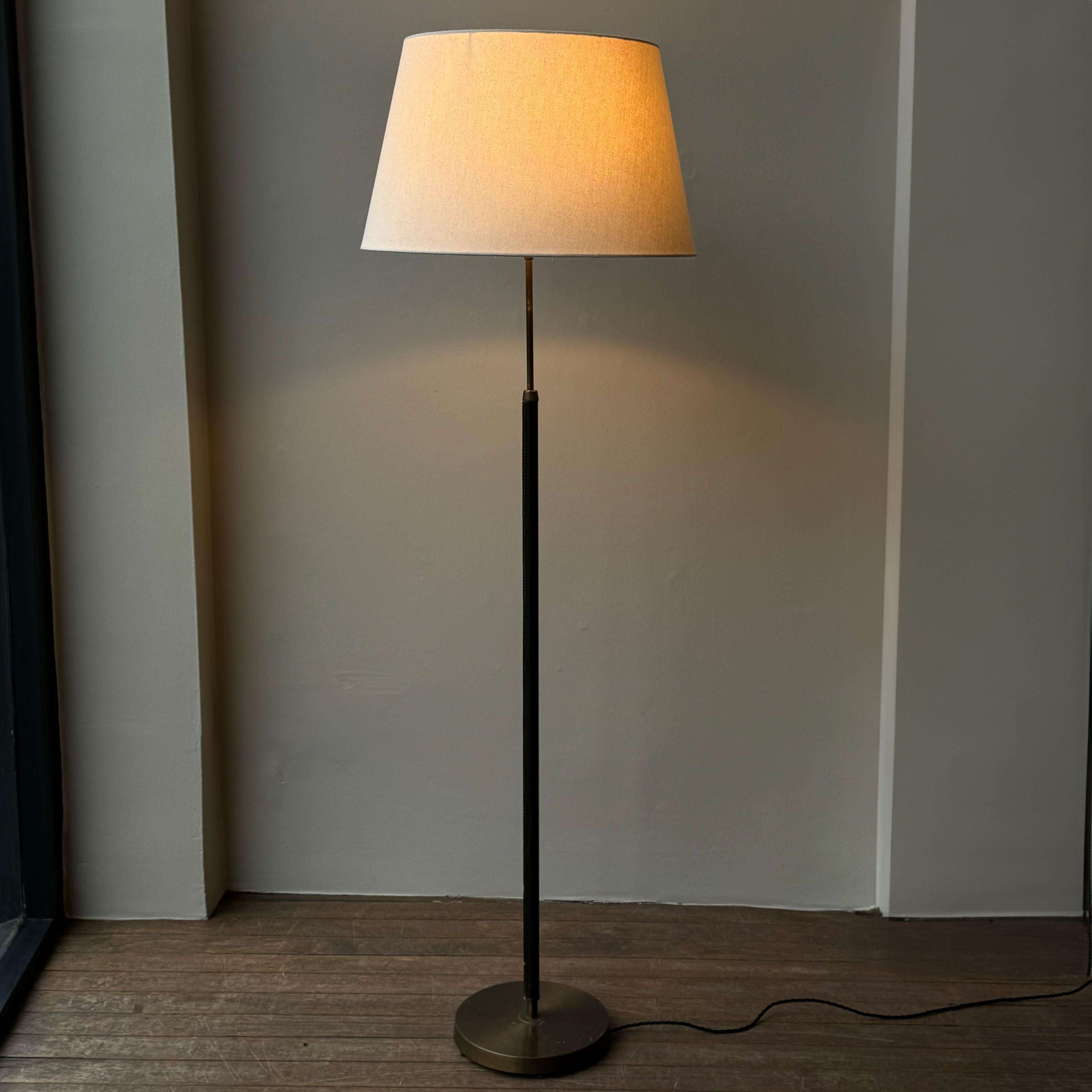 A petite leather bound brass floor lamp made in Sweden between 1950-1960 by Falkenbergs belysning. 

This beautifully proportioned and tactile floor lamp features a hand-stitched leather wrapped stem and evenly patinated base and upper stem. 

The