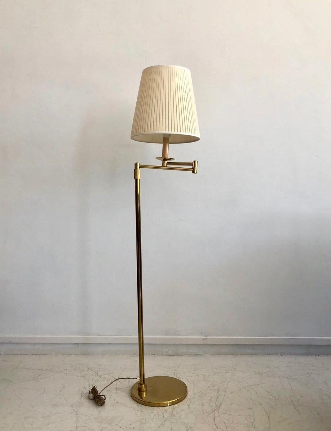 Brass floor lamp in the style of Hans-Agne Jakobsson with adjustable arm and cream-colored shade from circa 1980s. European plug. Great reading lamp due to its adjustable arm, which goes out up to 50 cm.