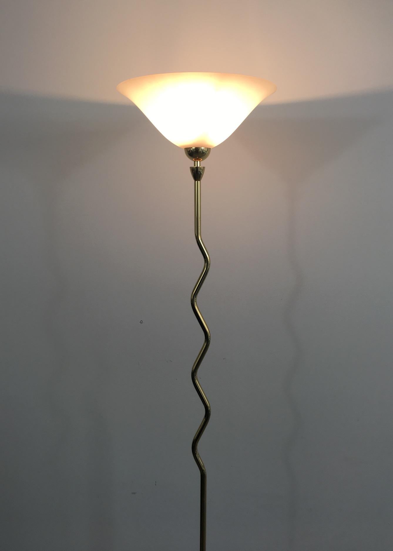 This brass floor lamp has a nice sinusoidal design and is ended by a frosted glass cup. This lamp is French, circa 1970.