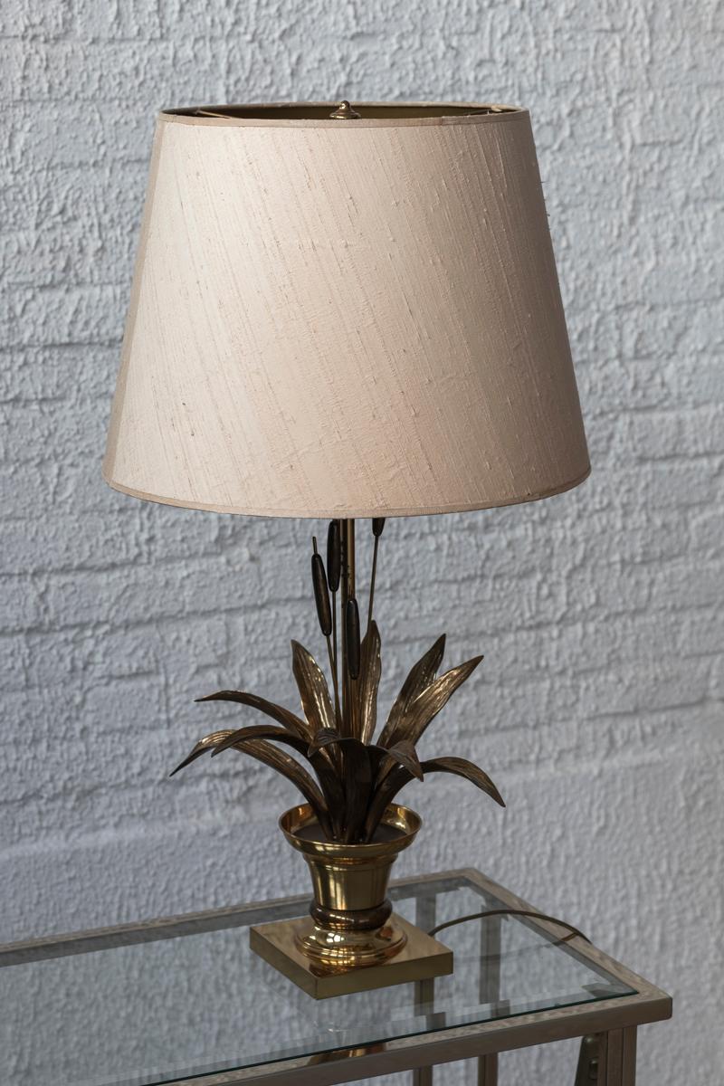 Brass table lamp attributed to Maison Charles in France, Hollywood Regency period, 1970s. This piece consists of a sculptural brass chrome base, in the shape of a vessel holding Cattail crops. Finished with a round, fabric-covered lamp shade. The