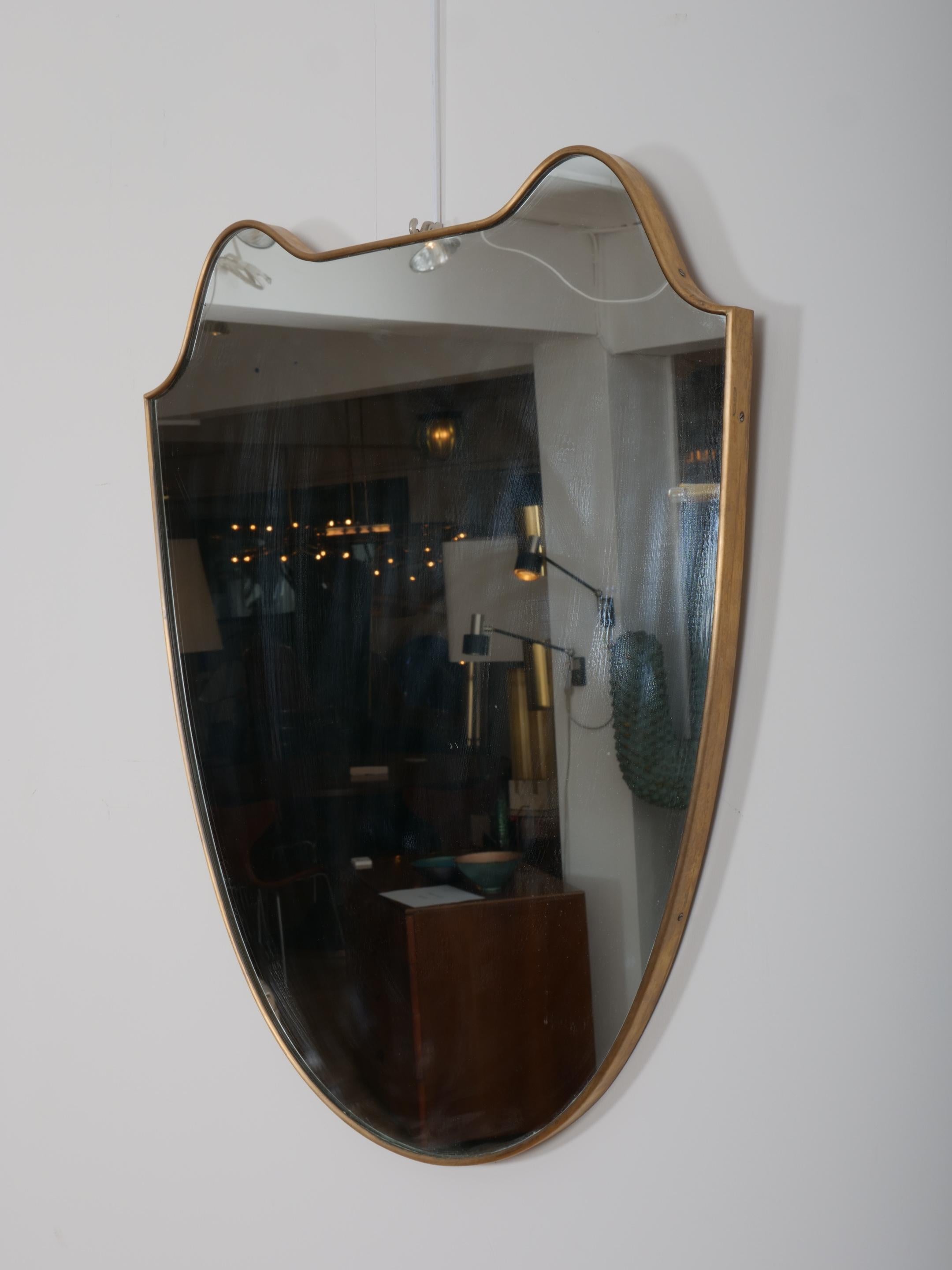 Mid-Century Modern Miroir en forme de bouclier avec cadre en laiton. Italie c1950 en vente