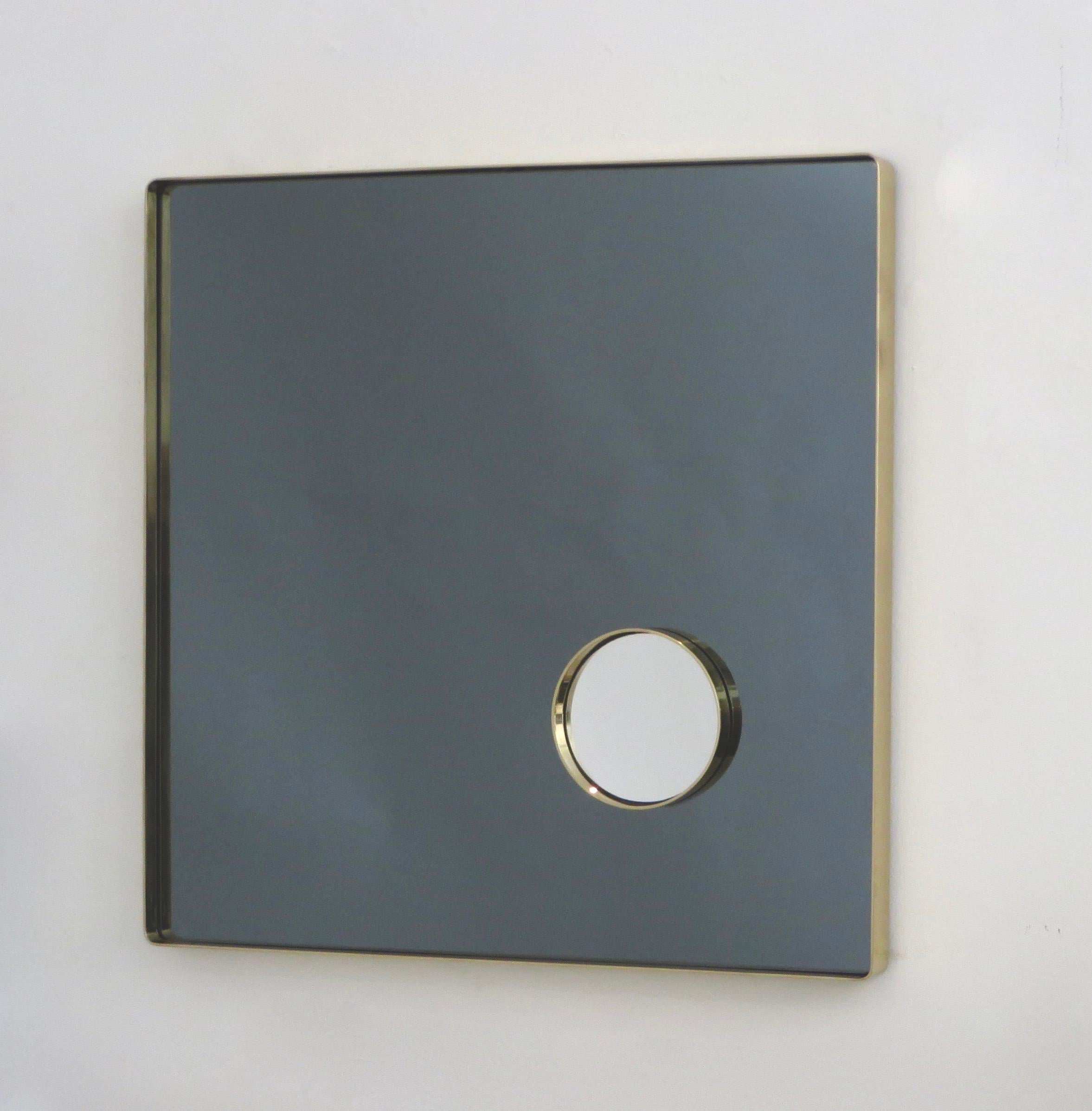 Italian brass framed square smoked light grey mirror with an inset brass framed clear circle of sorciere mirror attributed to Lino Sabattini.
The brass frame is in perfect condition with no pitting or discoloration.
The small inserted perfectly