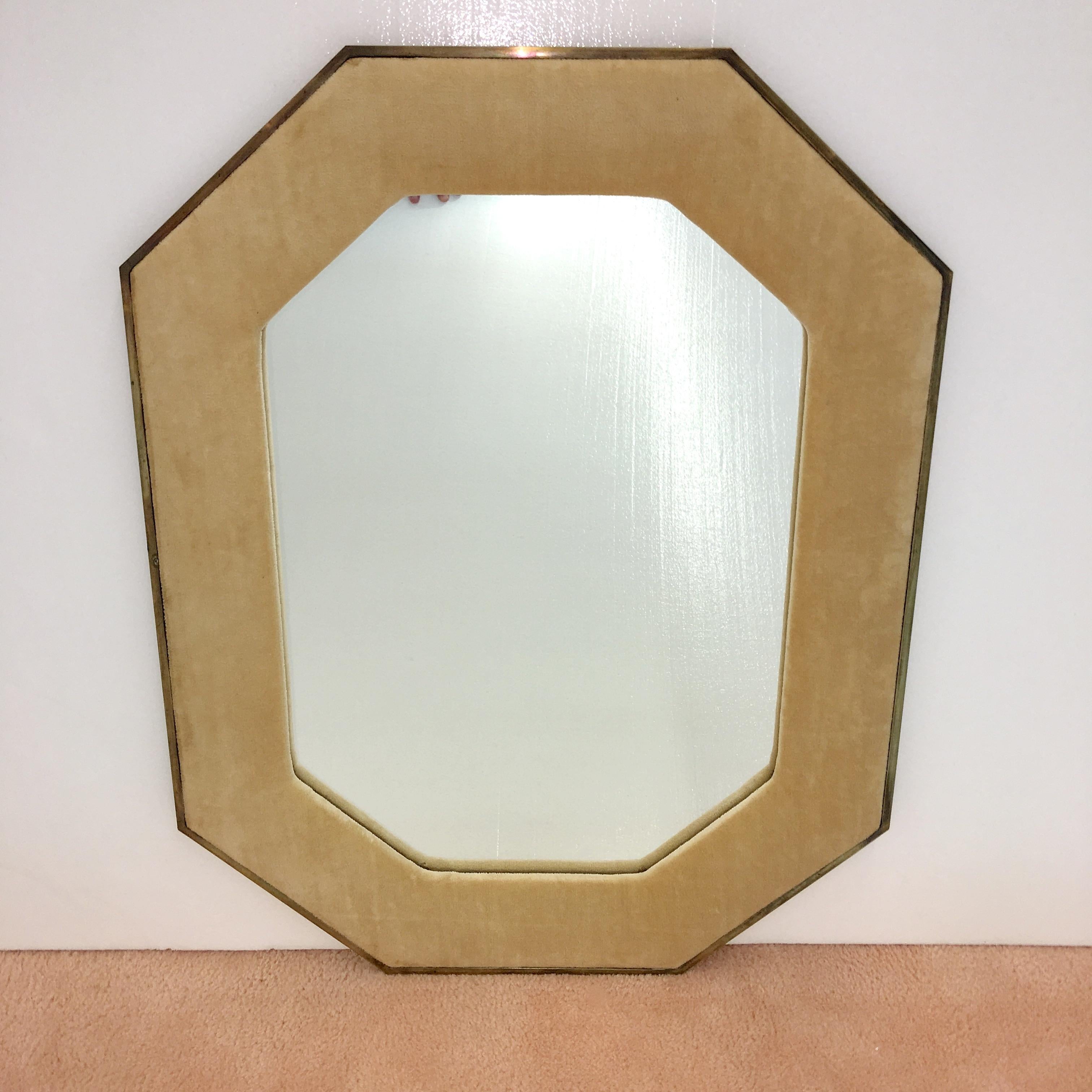High quality octagonal shaped mirror produced in 1960 by John Widdicomb for John Stuart.

Outer frame is slim solid brass with upholstered 4 inch inner border. Currently in its original beige chenille however it can be recovered in your own