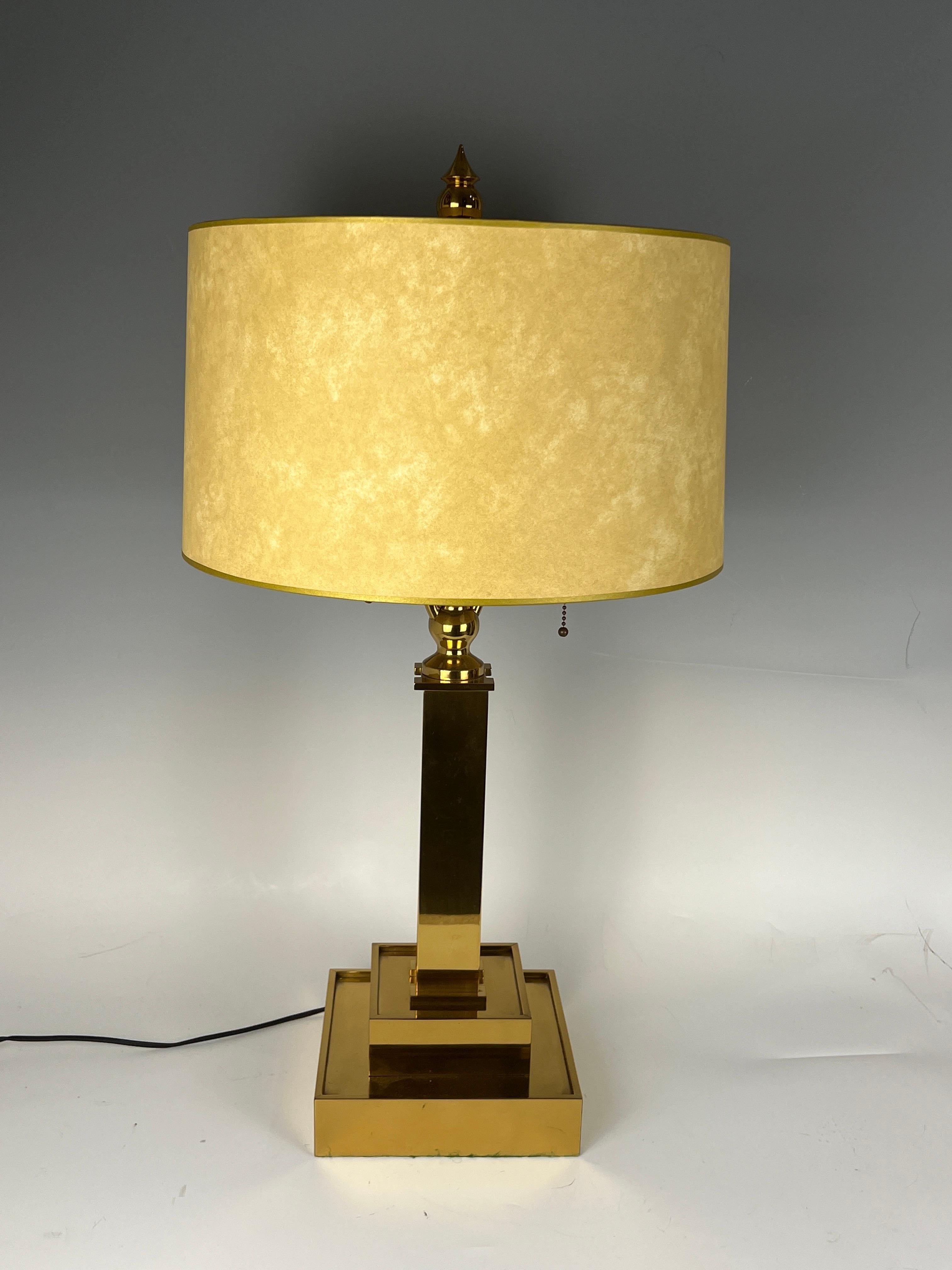 An Art Deco table lamp in brass with a beige color paper shade.
Made in France.