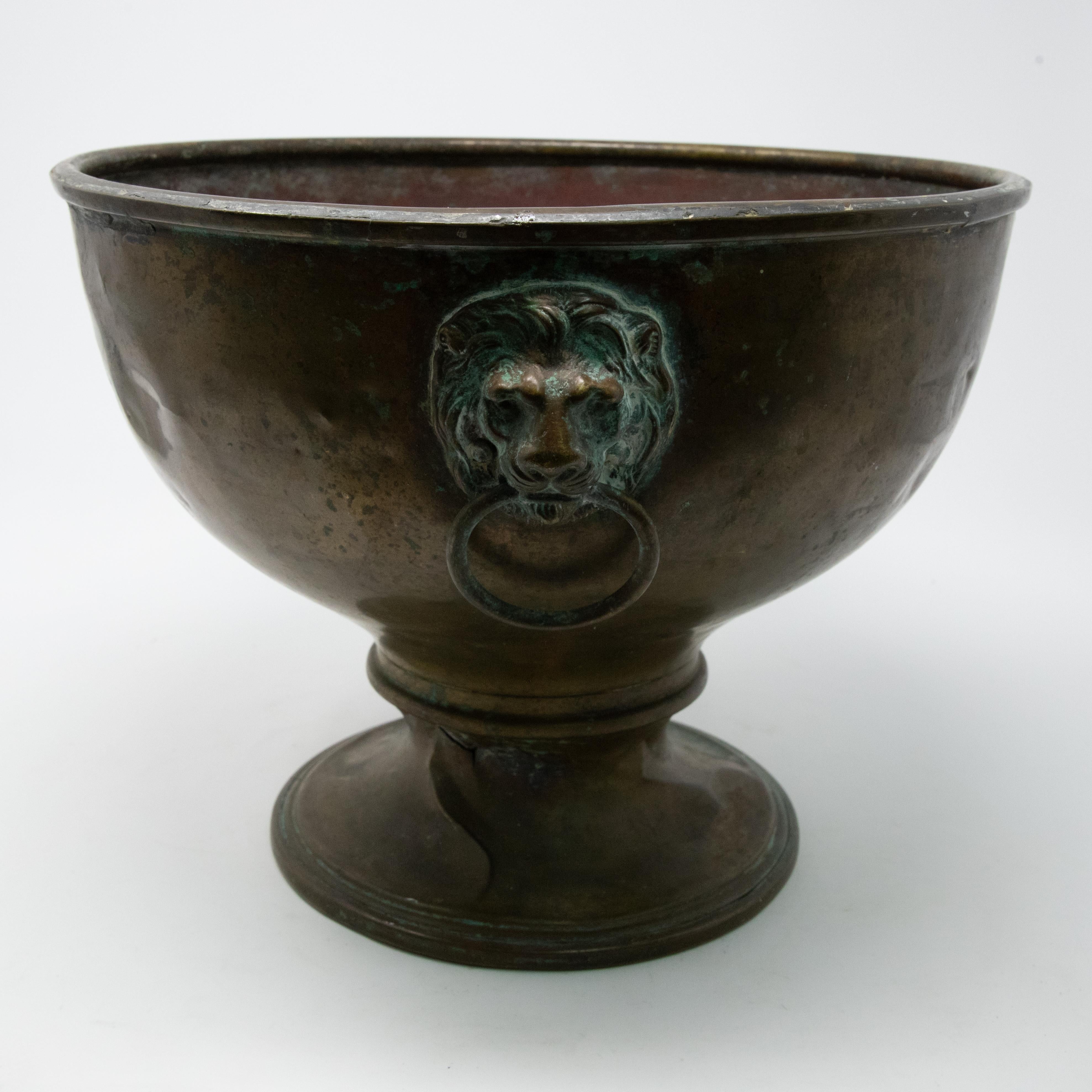 Offering this beautiful brass planter with lions heads. Starting on the bottom with a simple rounded plinth like base. From there graduates outward in a nice half spherical bowl. There are three lions heads placed around the planters body with rings