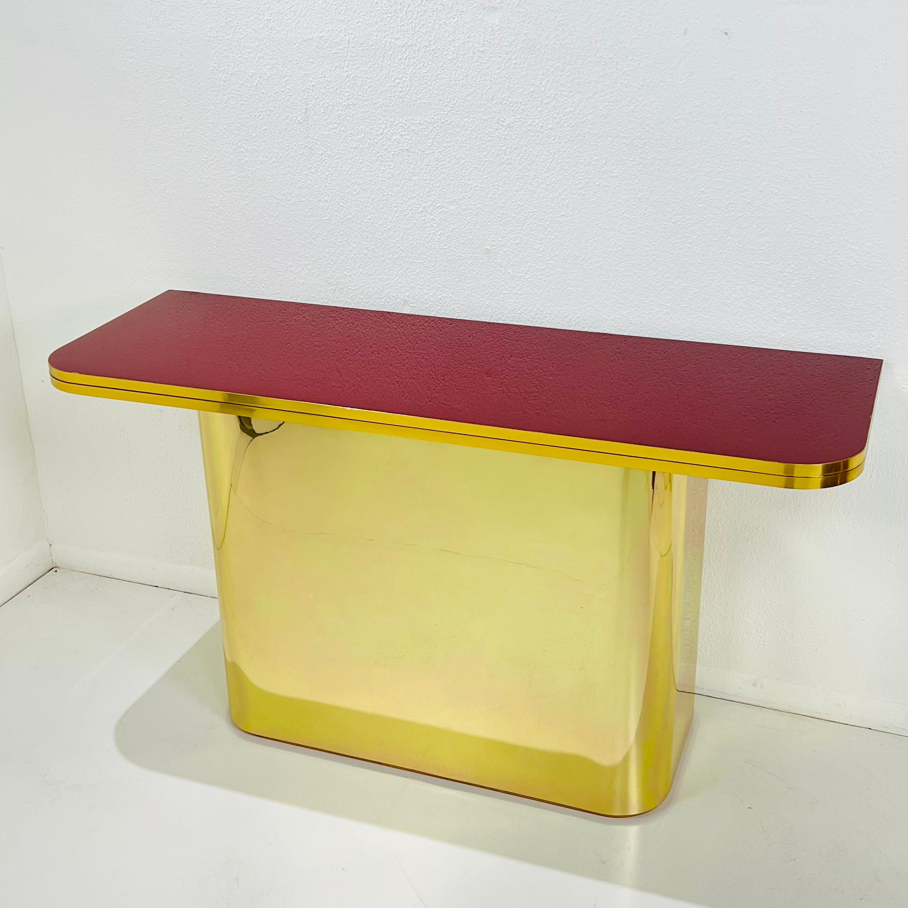 Awesome and totally unique vintage postmodern brass wrapped 3-way console table in the style of J.C. Mahey. Features a glossy garnet red lacquer flip top that slides and opens to convert to a rectangular top table. Base and top in good vintage