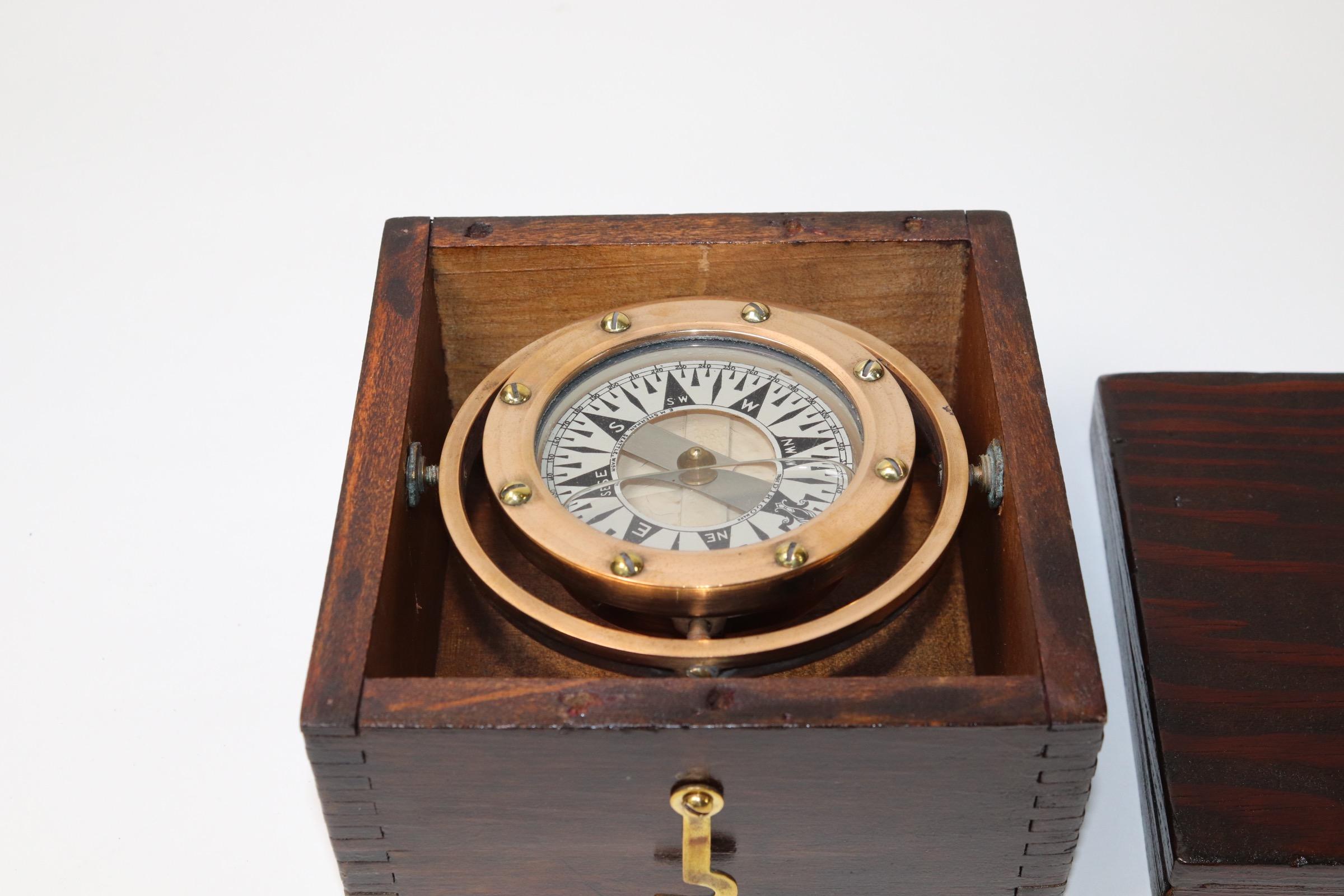 Polished brass boat compass by Dirigo mounted into a varnished wood box with lid and polished brasses. Weight is 3 pounds.
