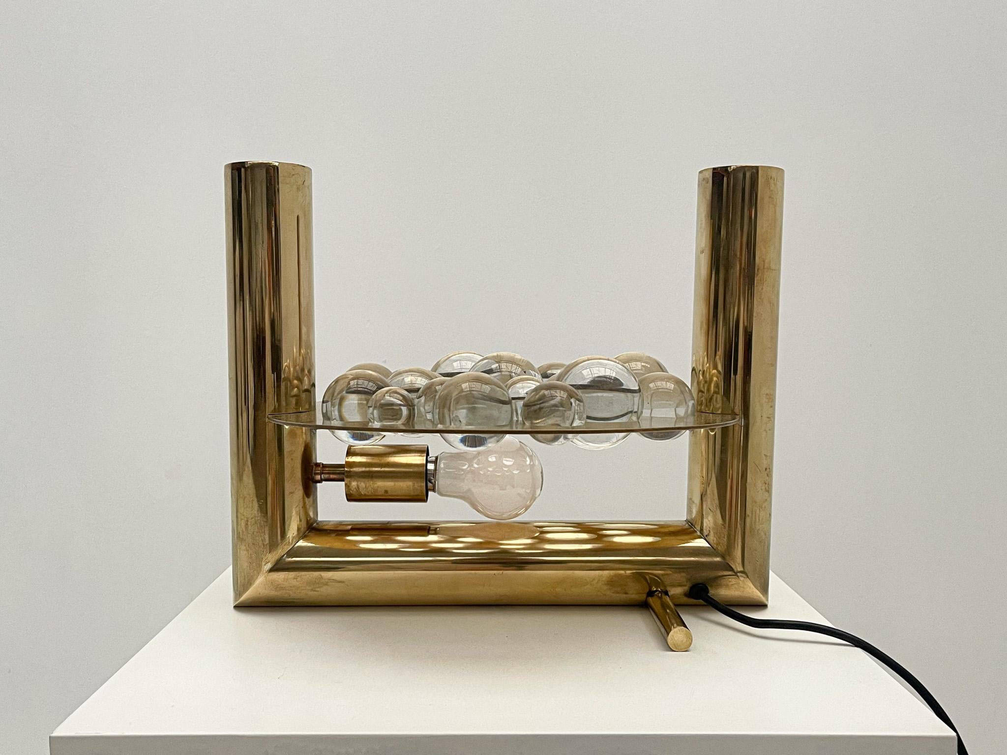 Une étonnante lampe de table italienne du milieu du siècle, fabriquée en laiton et ornée d'une délicate composition de boules de verre. Cette pièce intemporelle allie un savoir-faire élégant à un design sculptural unique. Le cadre en laiton présente