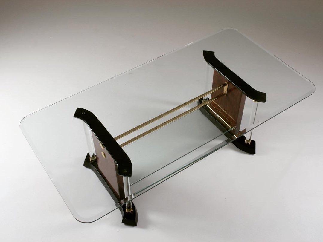 Two-level coffee table dating from the 1970s. Elegance perfectly characterizes this table combining black lacquered wood, brass. The glass is also present at the level of the columns and the upper plate is bevelled. 4 small chips (2mm) are to be