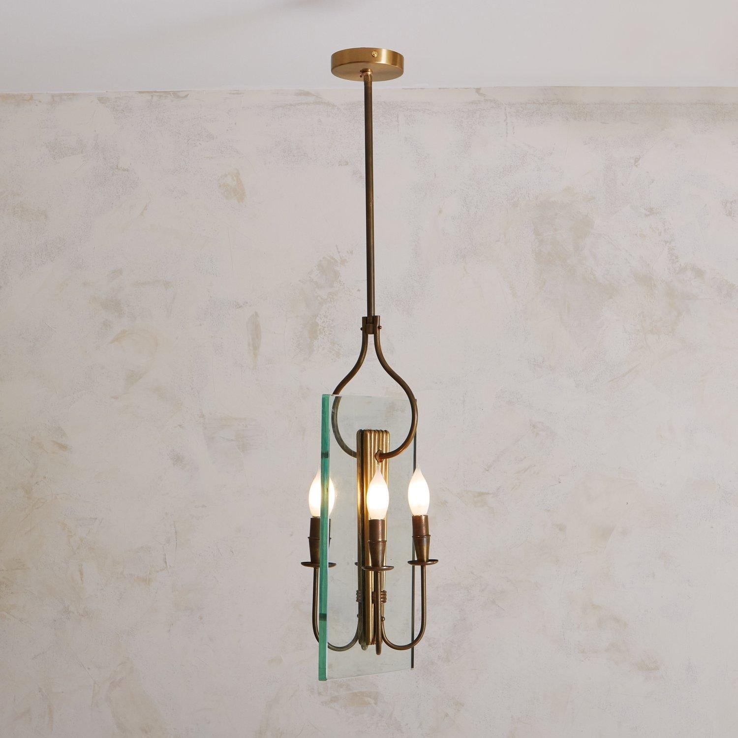 A mid-century pendant light in the style of Fontana Arte featuring a rectangular glass frame with a fluted brass center. It hangs from a brass canopy with a sculptural rod and has four curved arms which hold candelabra bulbs. Sourced in France, 20th
