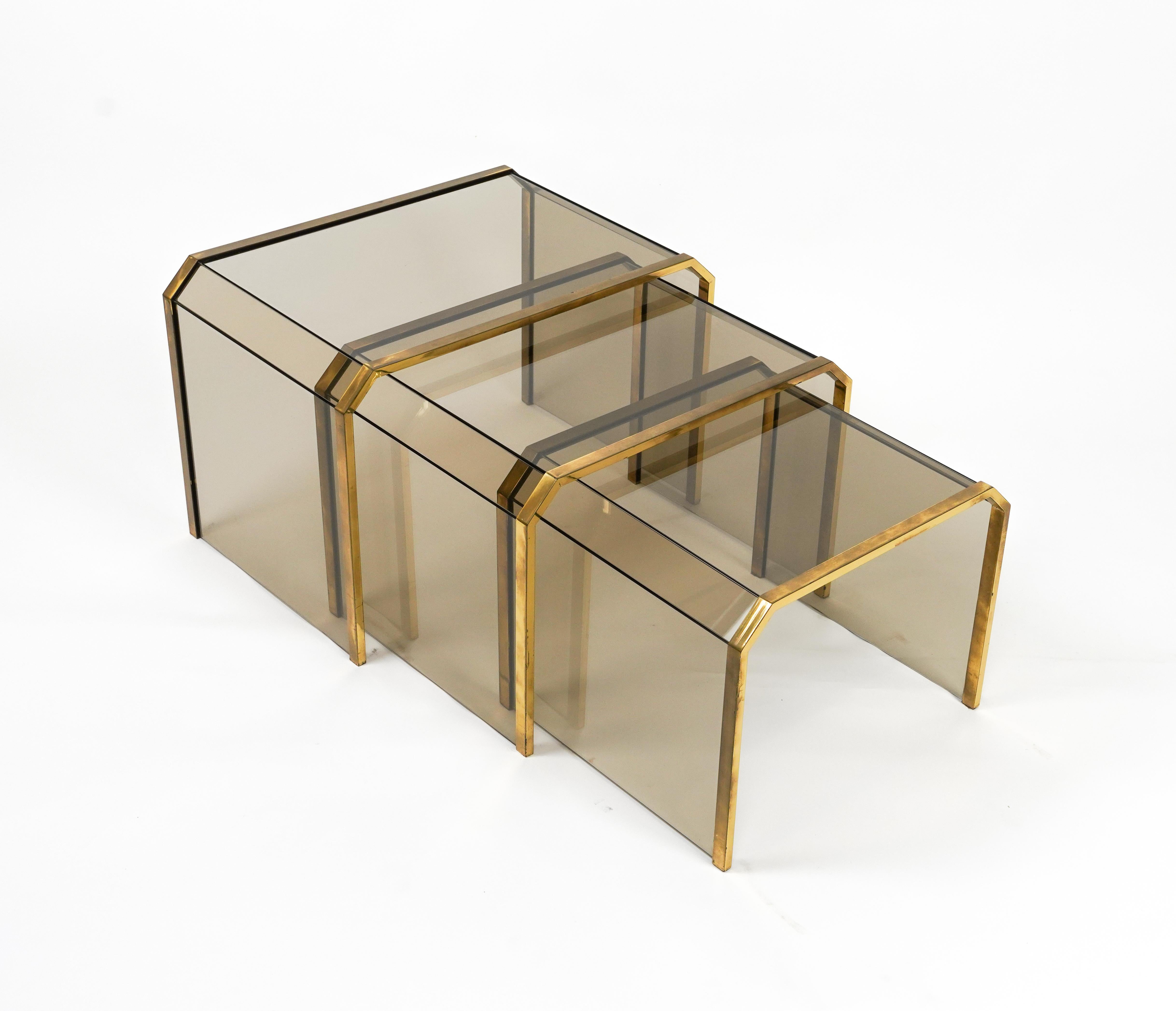 Midecentury amazing set of three nesting table in brass and smoked glass in the style of Gallotti & Radice.

Made in Italy in the 1970s.

Dimensions:  
Biggest table: 40.5 H x 59.5 W x 39.5 D cm 
Middle table: 37.5 H x 52.5 W x 39.5 D cm 
Smallest