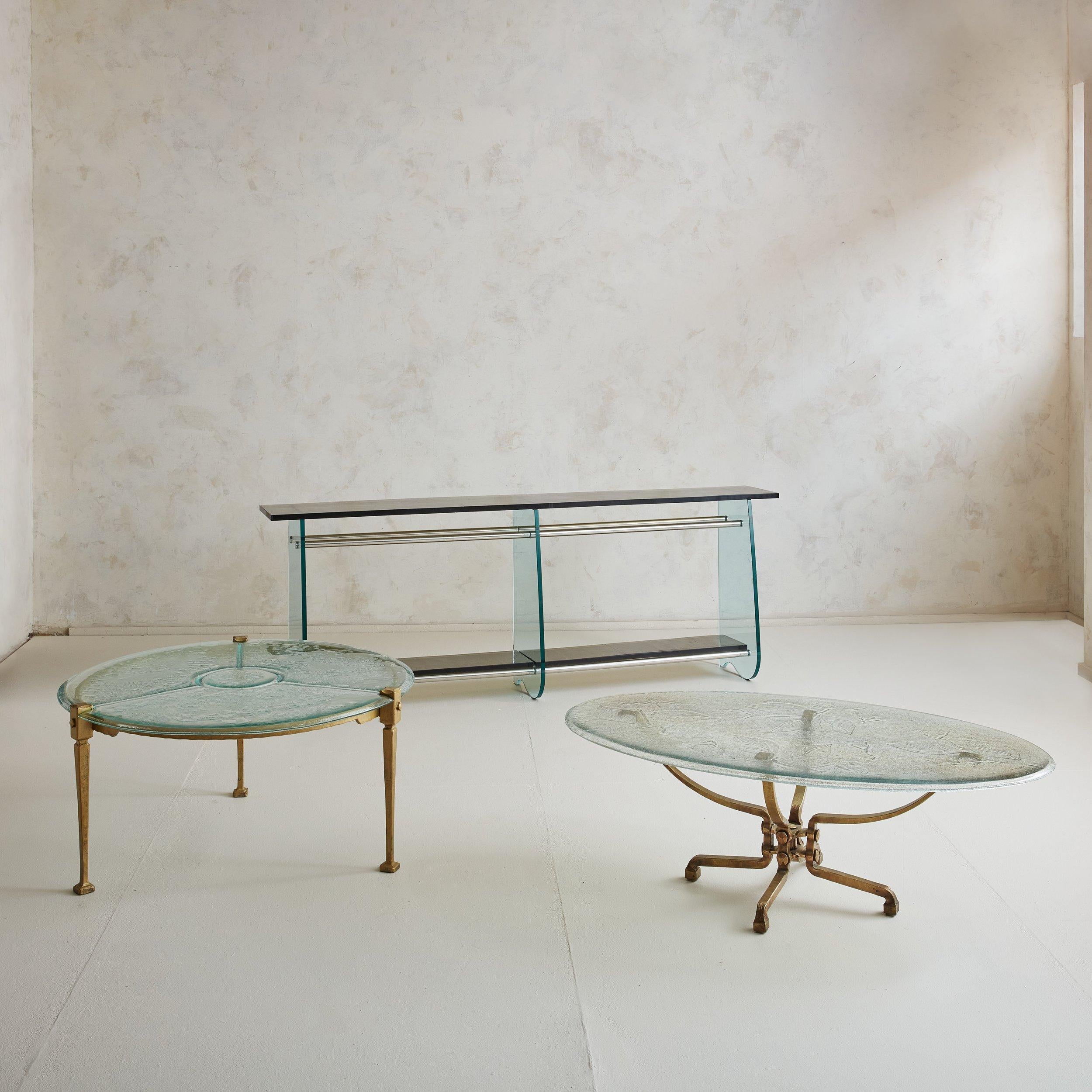 A rare brutalist brass and glass top round coffee table by German designer Lothar Klute. This coffee table features a brass frame with natural patina, three tapered legs, and square feet. A gorgeous geometric design in etched into the aqua hued