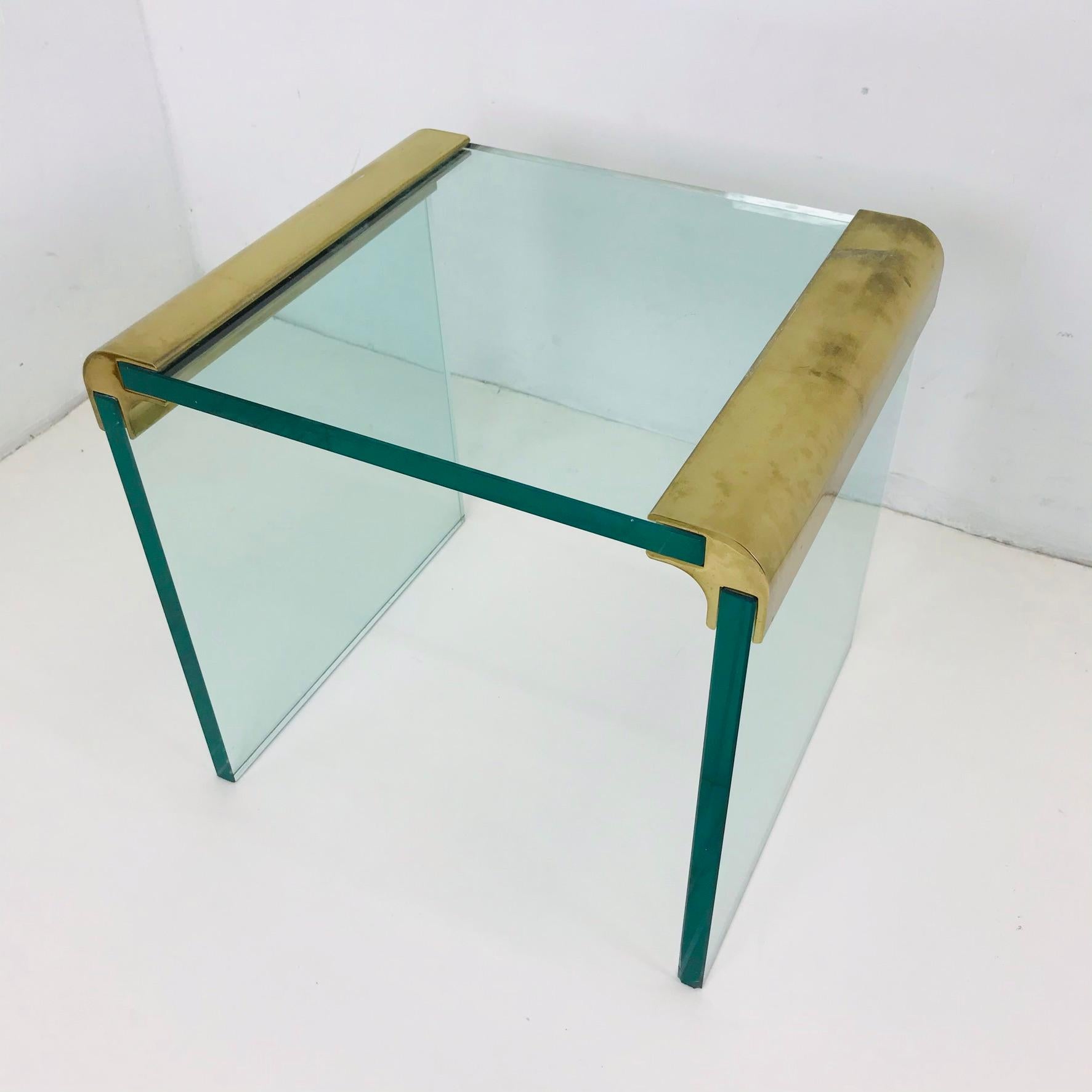 This beautiful brass and glass waterfall side table is from the Pace Collection by Leon Rosen. It is a vintage piece from the 1970s that reflects the Minimalist design aesthetic that emerged from Mid-Century Modern styles. Highly functional without