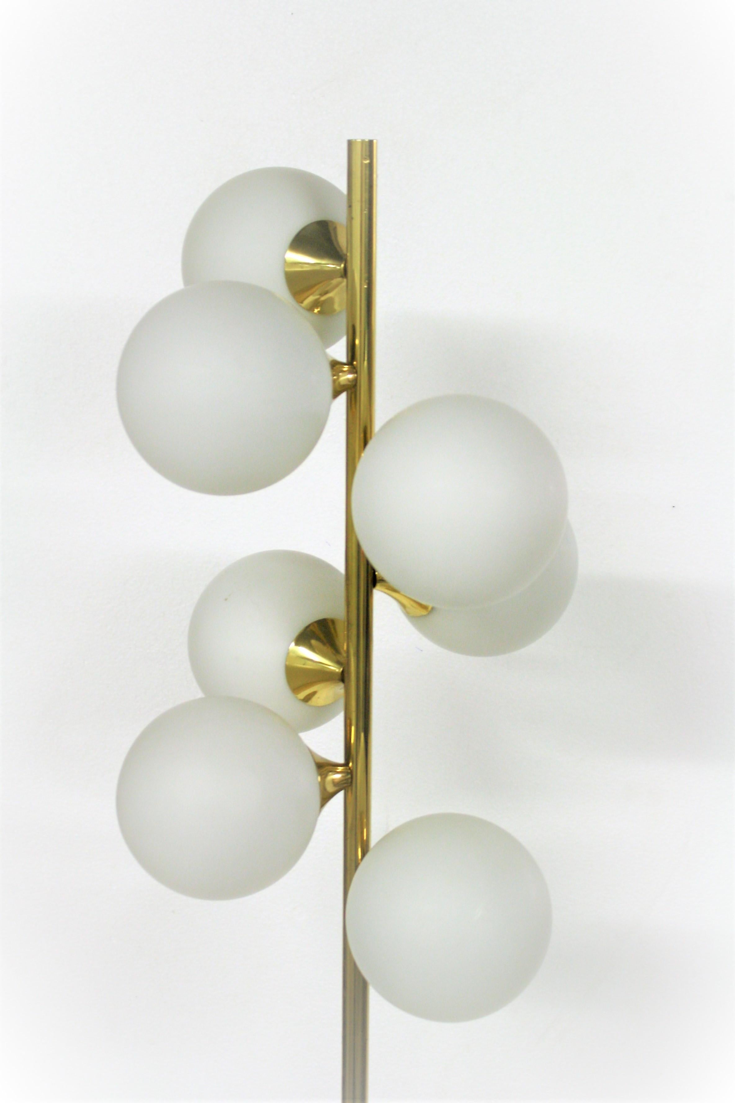 Mid-Century Modern spiral brass floor lamp with seven white glass globe shades.

This sixties lamp emits a warm light, creates a lovely atmosphere and has a timeless design.

The floor lamp is very much in the style of Stilnovo floor lamps but