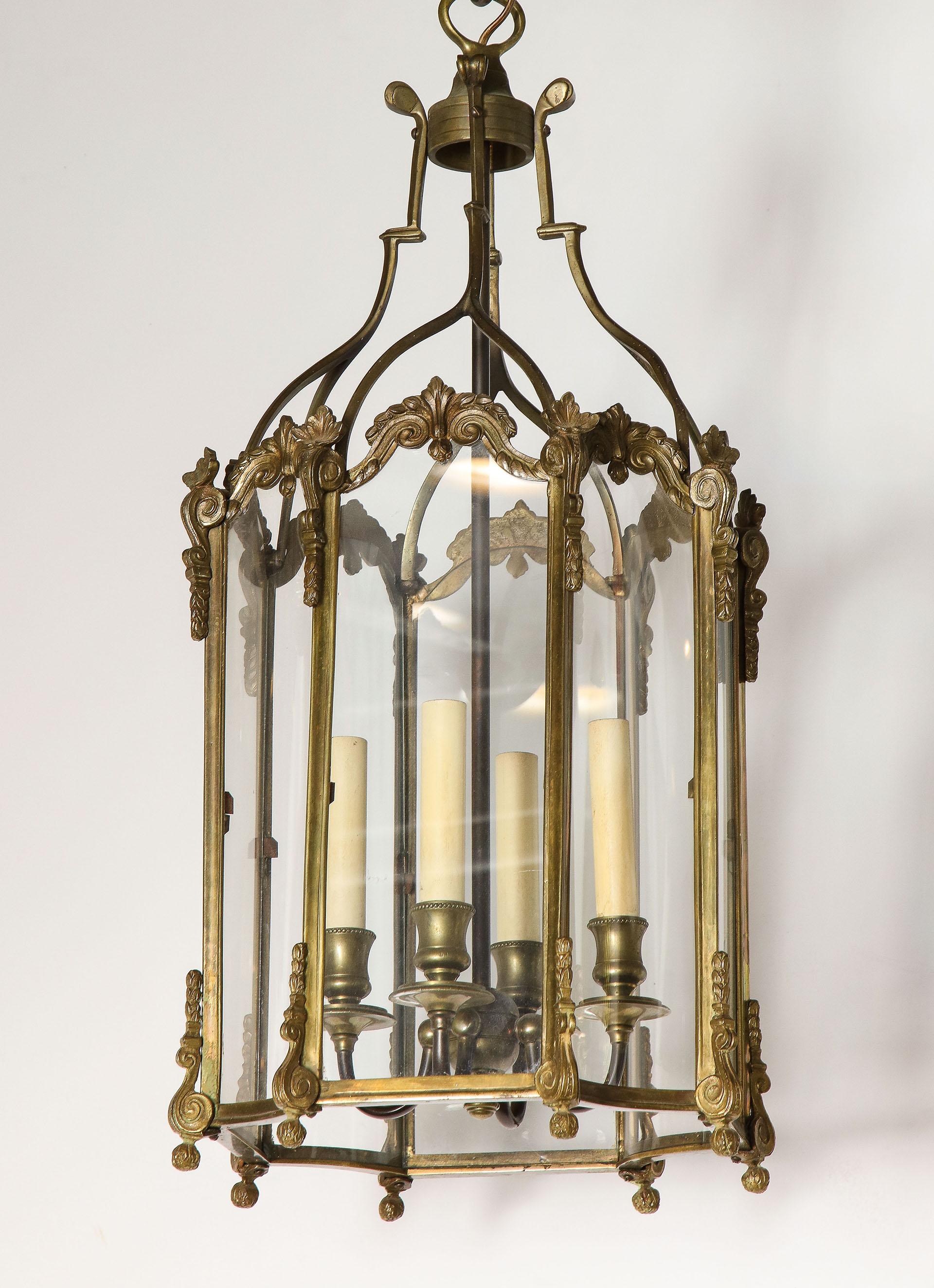 Each octagonal shaped lantern with alternating glass plates and concave glass plates set into a stylize brass frame with an interior cluster of 4-light.