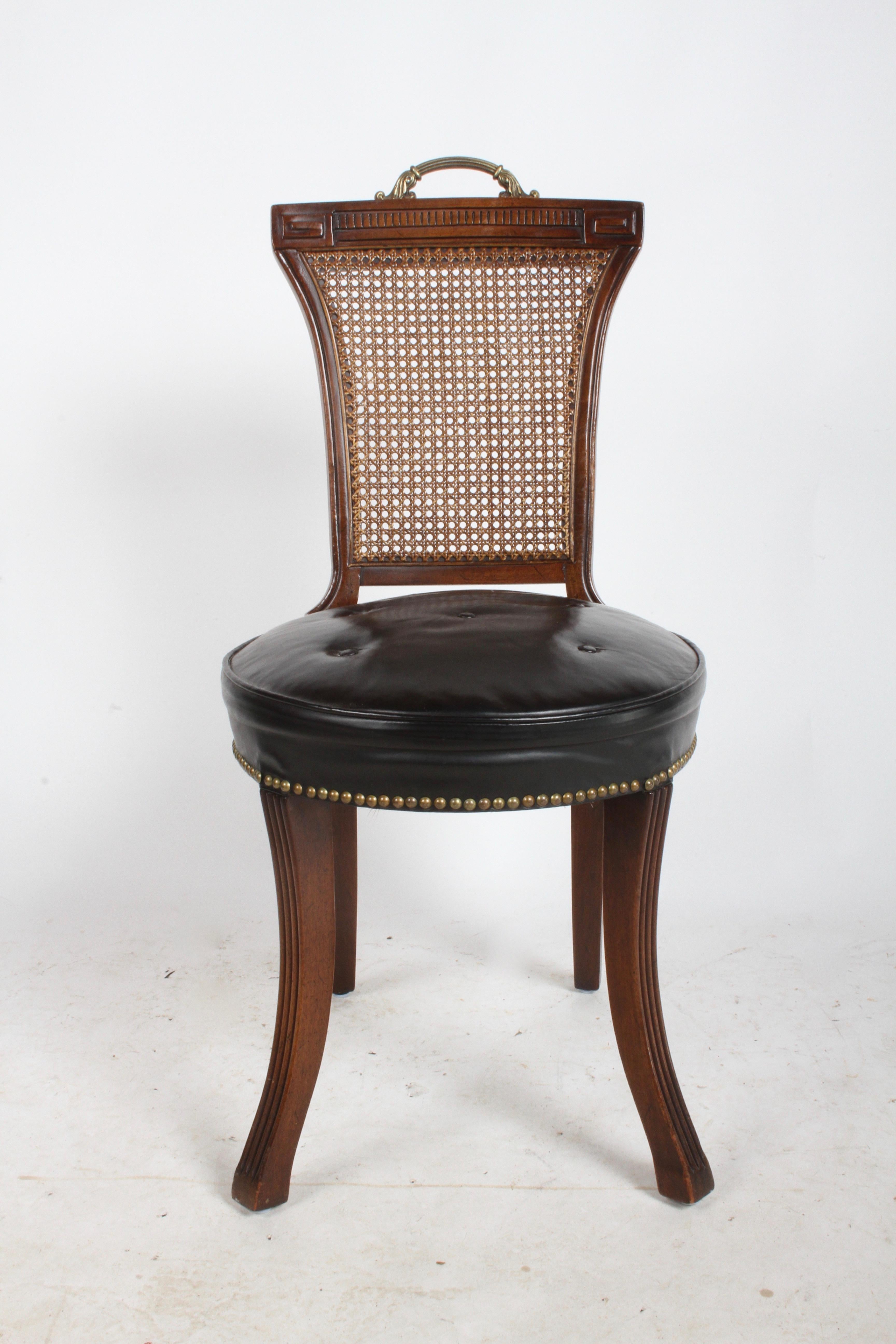 In the style of Grosfeld House mahogany frame desk chair with brass handle, caned back, Greek key design, splayed fluted legs and black leather seat. Original leather seat, has some stress marks, four buttons and brass tacks. Original finish, some