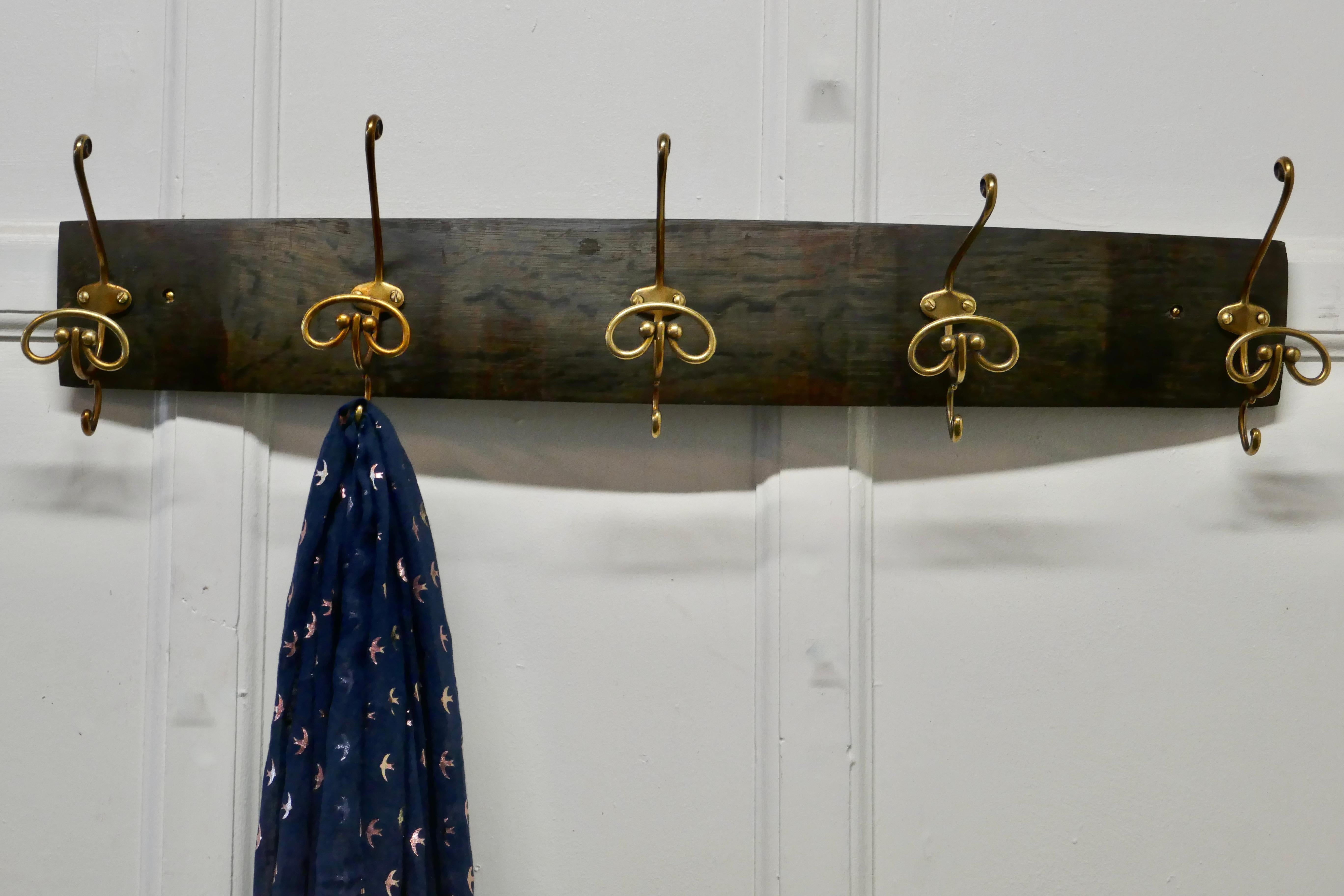 Brass hat and coat hooks, set on wine barrel oak

This is a solid piece of oak taken from a French wine barrel, it has 5 French brass scroll hat and coat hooks fixed to it 
The rack is slightly curved and has several display uses 
The rack is 6”
