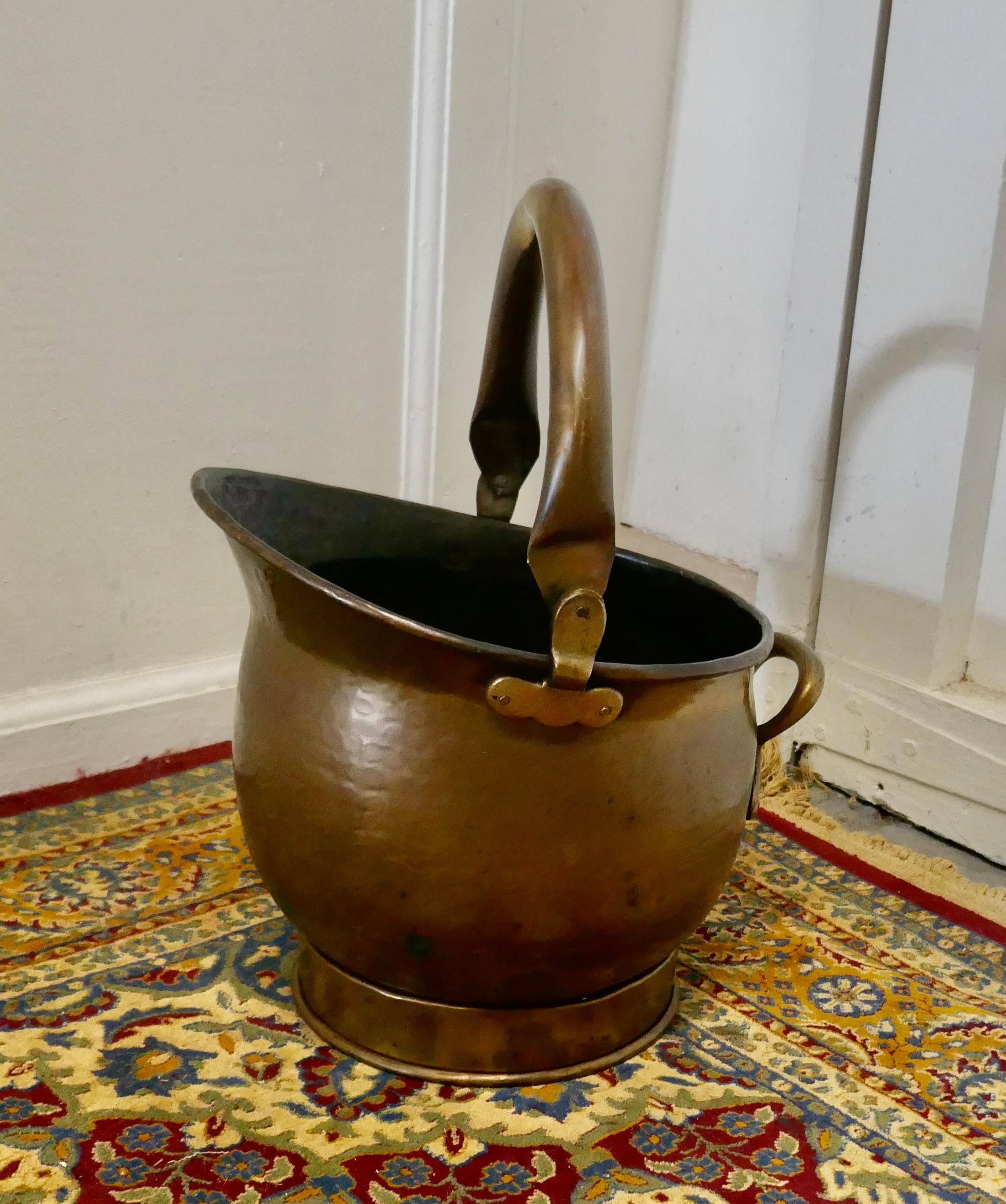 Brass helmet coal scuttle 

This bucket is a very attractive helmet shape, it is in age darkened Brass with riveted hooped brass handles, both back and top
The Scuttle is in good used condition and lots of character and is ready to go to work and