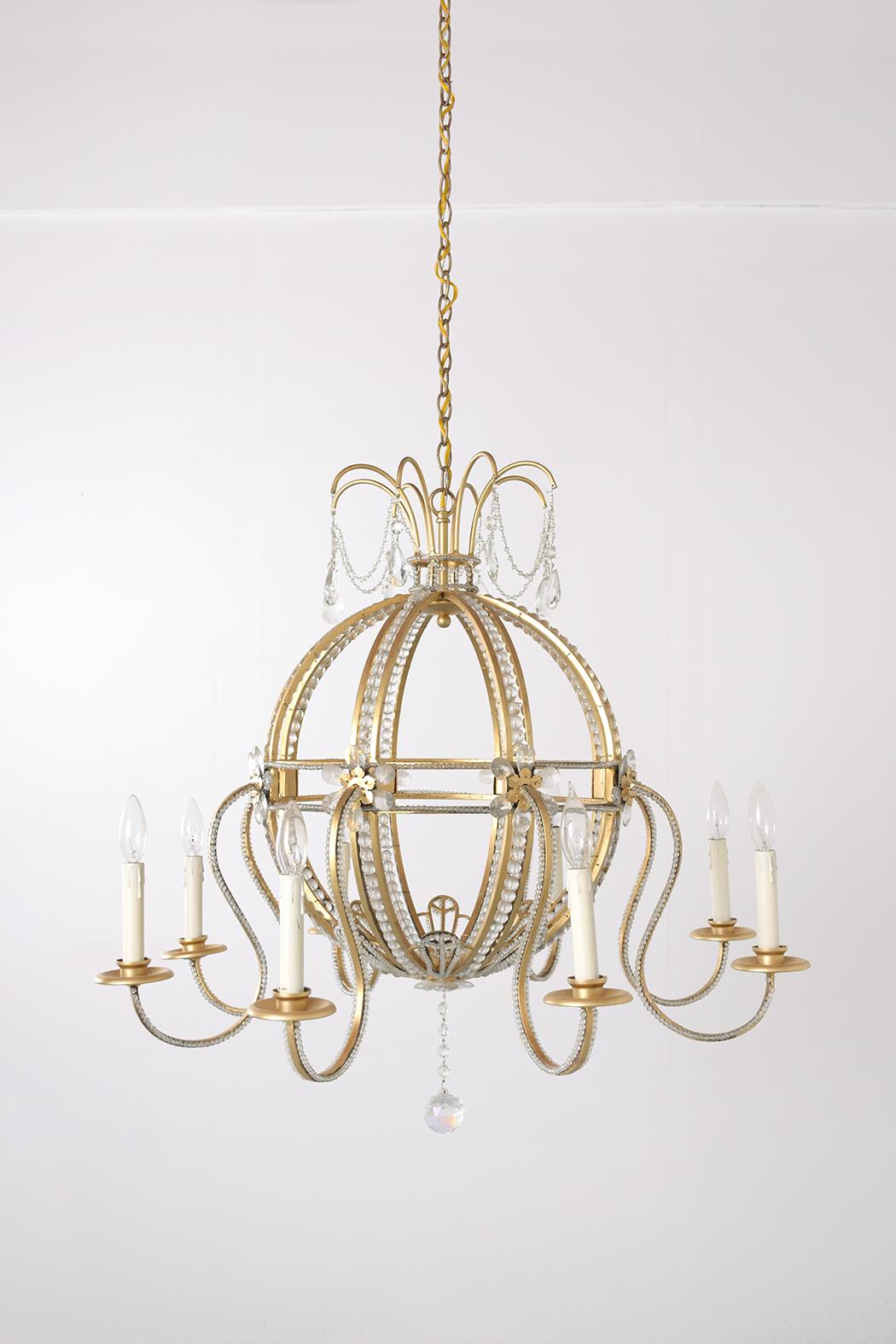 Illuminate your space with the grandeur of the past, brought to life in our extraordinary vintage brass crystal Hollywood Regency chandelier from the 1910s. This stunning piece, newly restored by our skilled team of craftsmen, is a blend of timeless