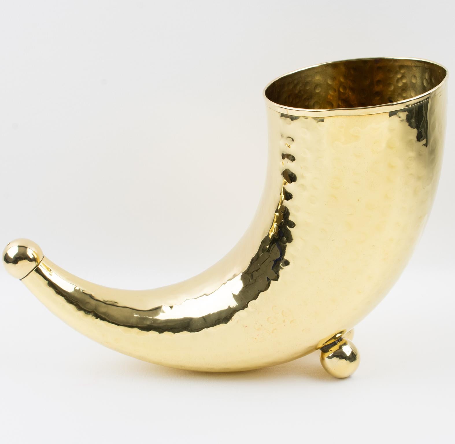 This stylish modernist brass wine cooler or vase features an ultra-chic versatile use with a whimsical minimalist horn of plenty with bead feet and high glossy metal with a slightly hammered finish. Lots of character, bold lines, and flawless