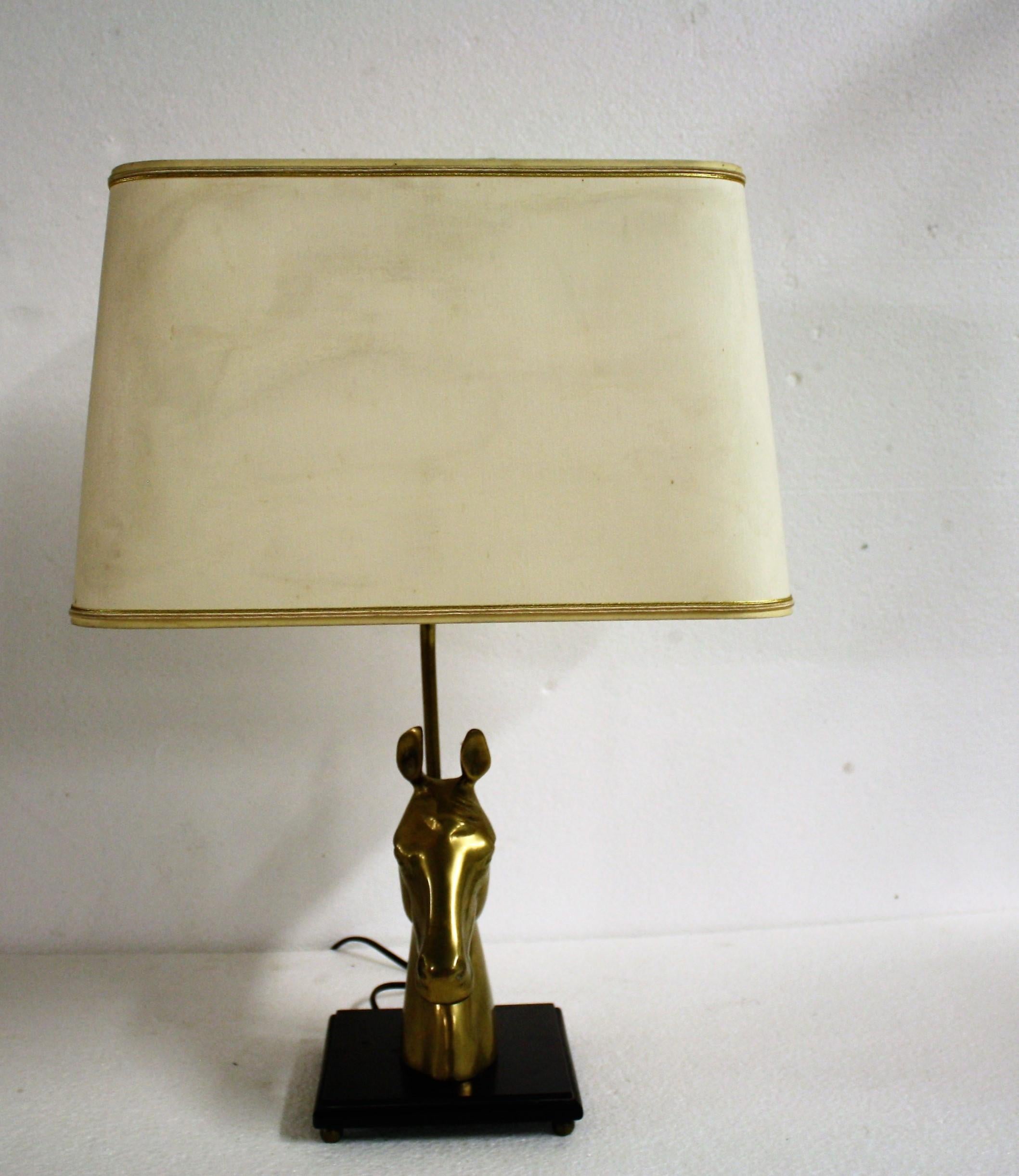Brass horse head table lamp in the style of Maison Jansen.

The brass horse head is mounted on a wooden base and finished with a period fabric shade.

Stylish table lamp with a luxurious appeal.

The height of the lampshade is